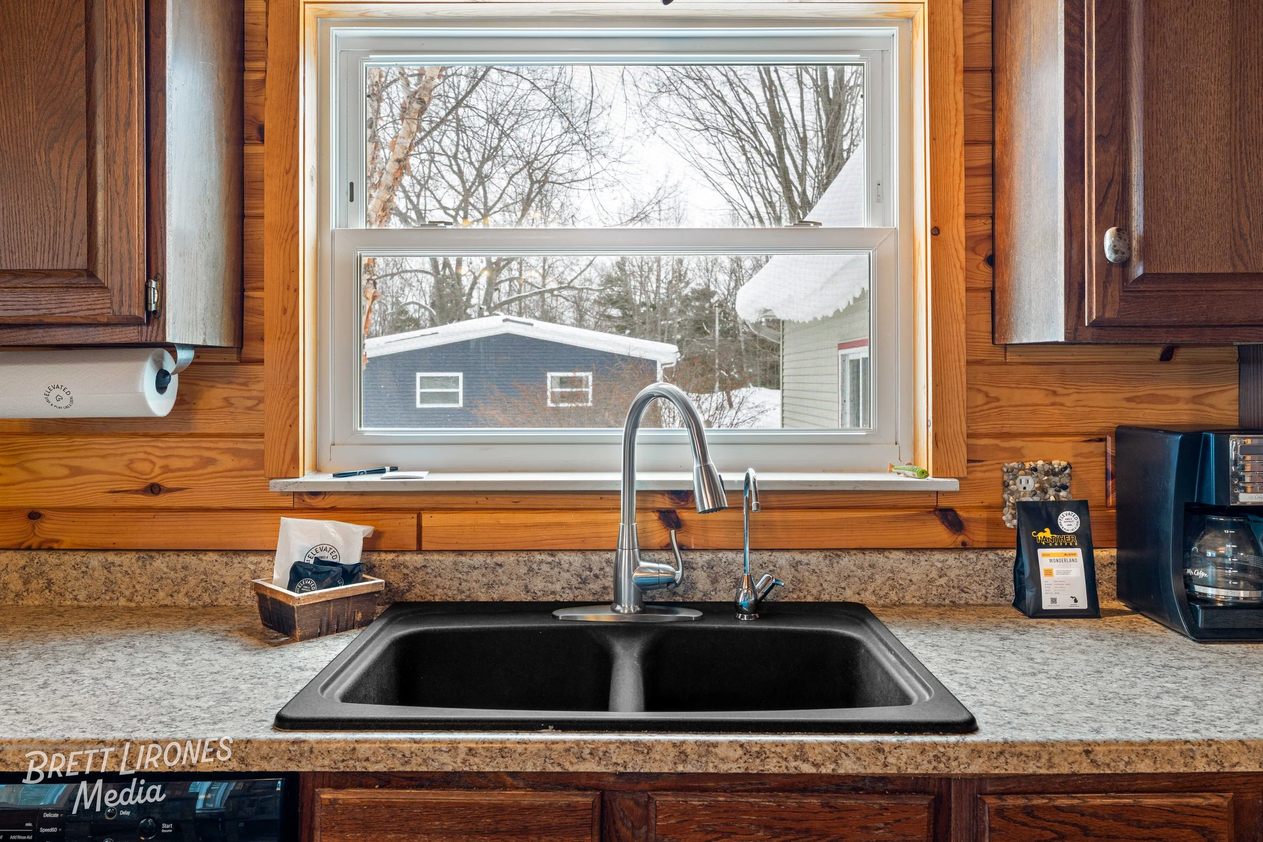 Kitchen sink with a window showing a snowy outdoor scene and a dark blue building.