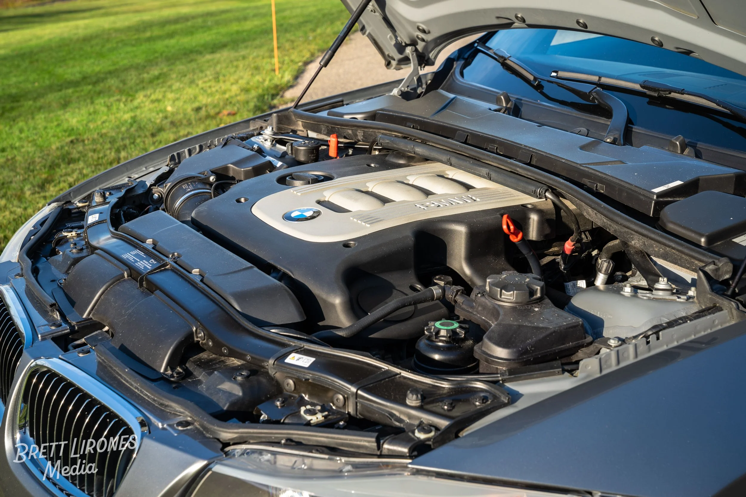 Open car hood showing engine bay of a BMW vehicle with engine cover and various components visible