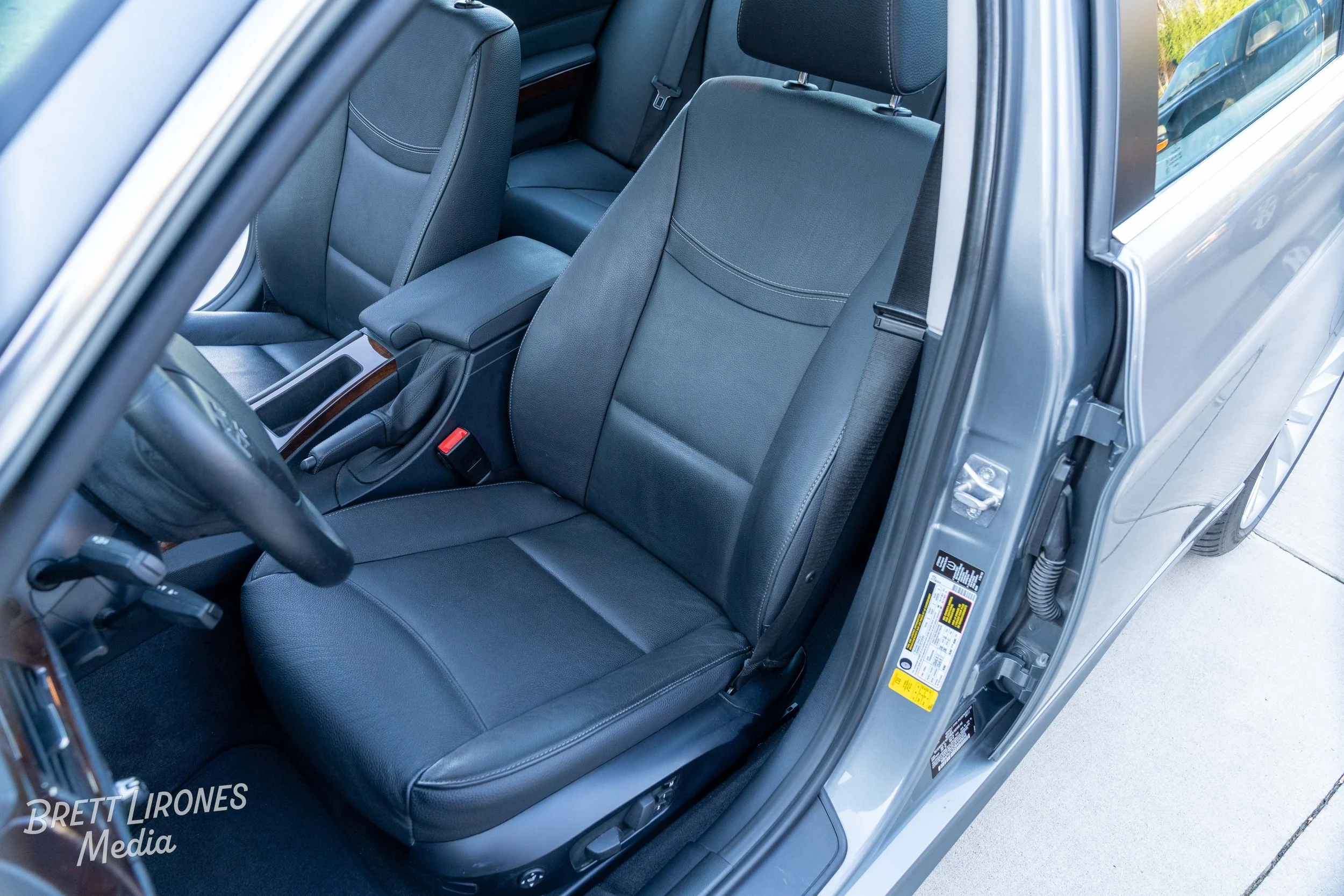 The interior of a silver car showing the front driver and passenger seats, with black leather upholstery, a center console, and part of the steering wheel visible.