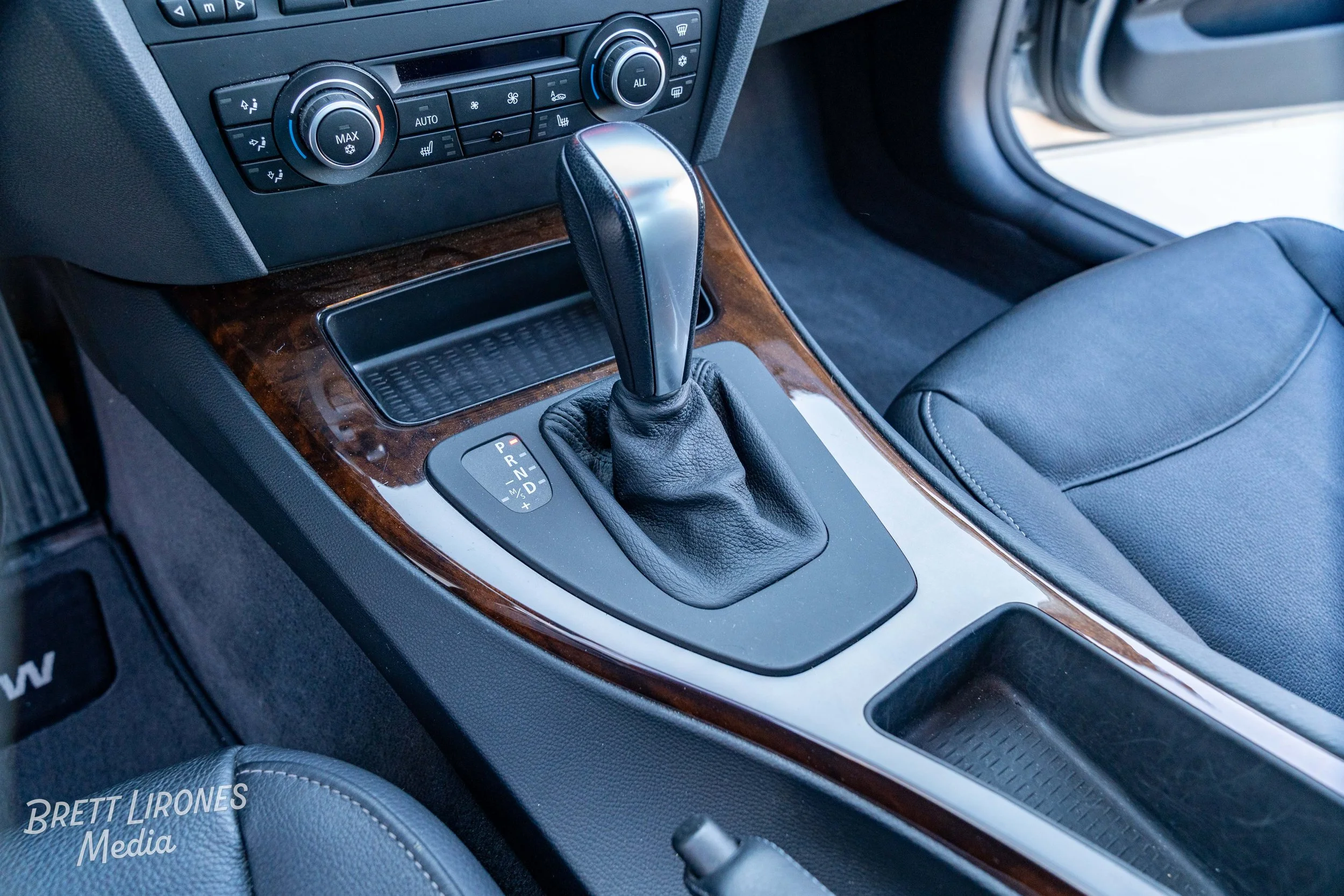 Automatic gear shift lever inside a car with a wooden trim center console.