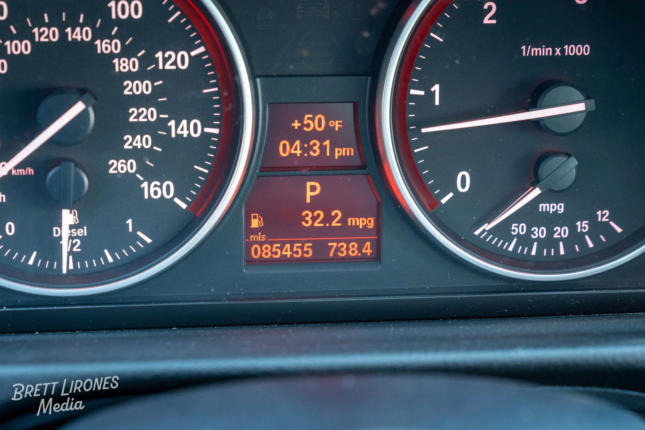 Car dashboard showing speedometer, tachometer, and digital display with temperature, time, fuel efficiency, and odometer readings.