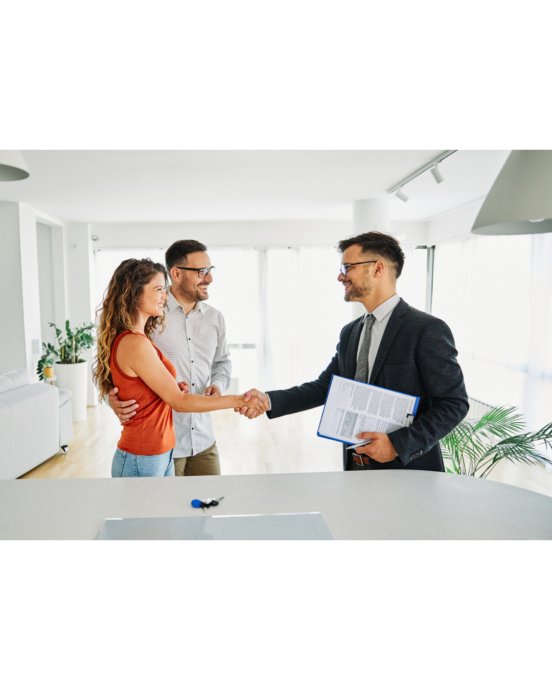 A couple shaking hands with a real estate agent in a bright living room.