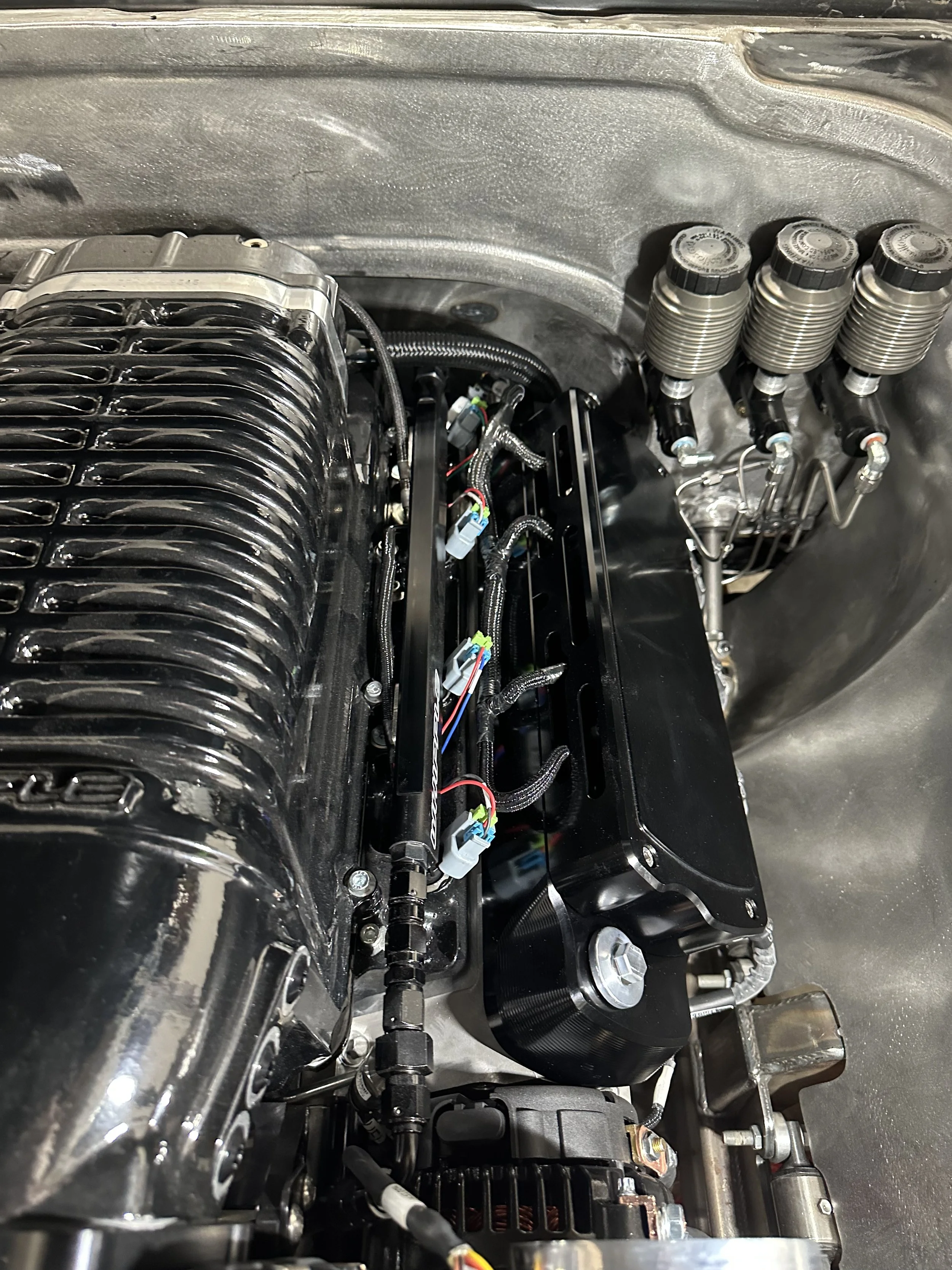 Close-up of a high-performance engine with black intake manifold, wiring, and fuel injectors in a car engine bay.