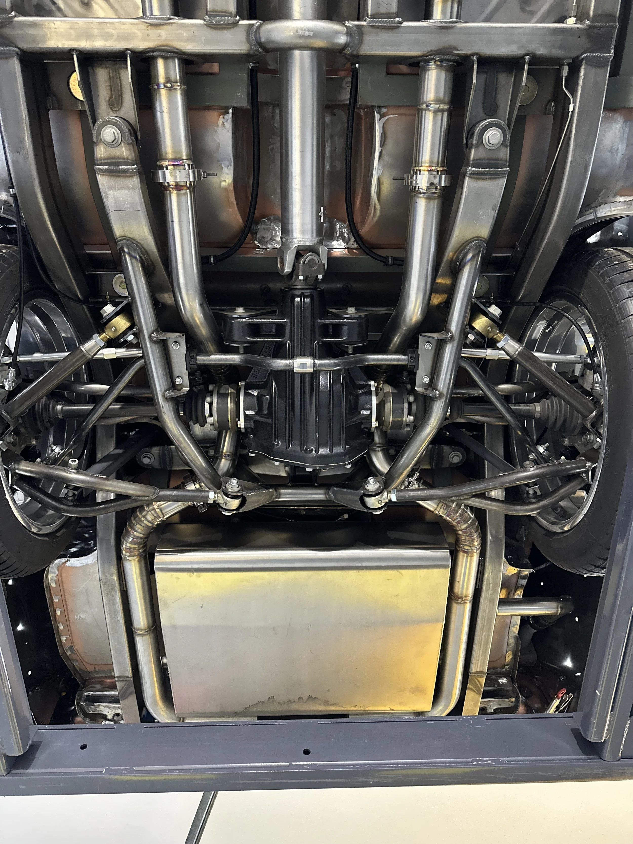 Underbody view of a high-performance car chassis showing exhaust pipes, suspension components, and the transmission.