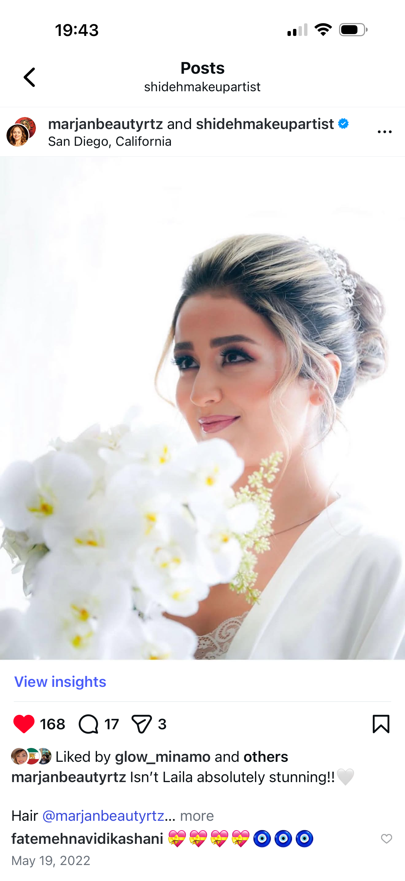 A bride with styled hair in an updo, holding a bouquet of white orchids, looking slightly to the side with a soft smile.