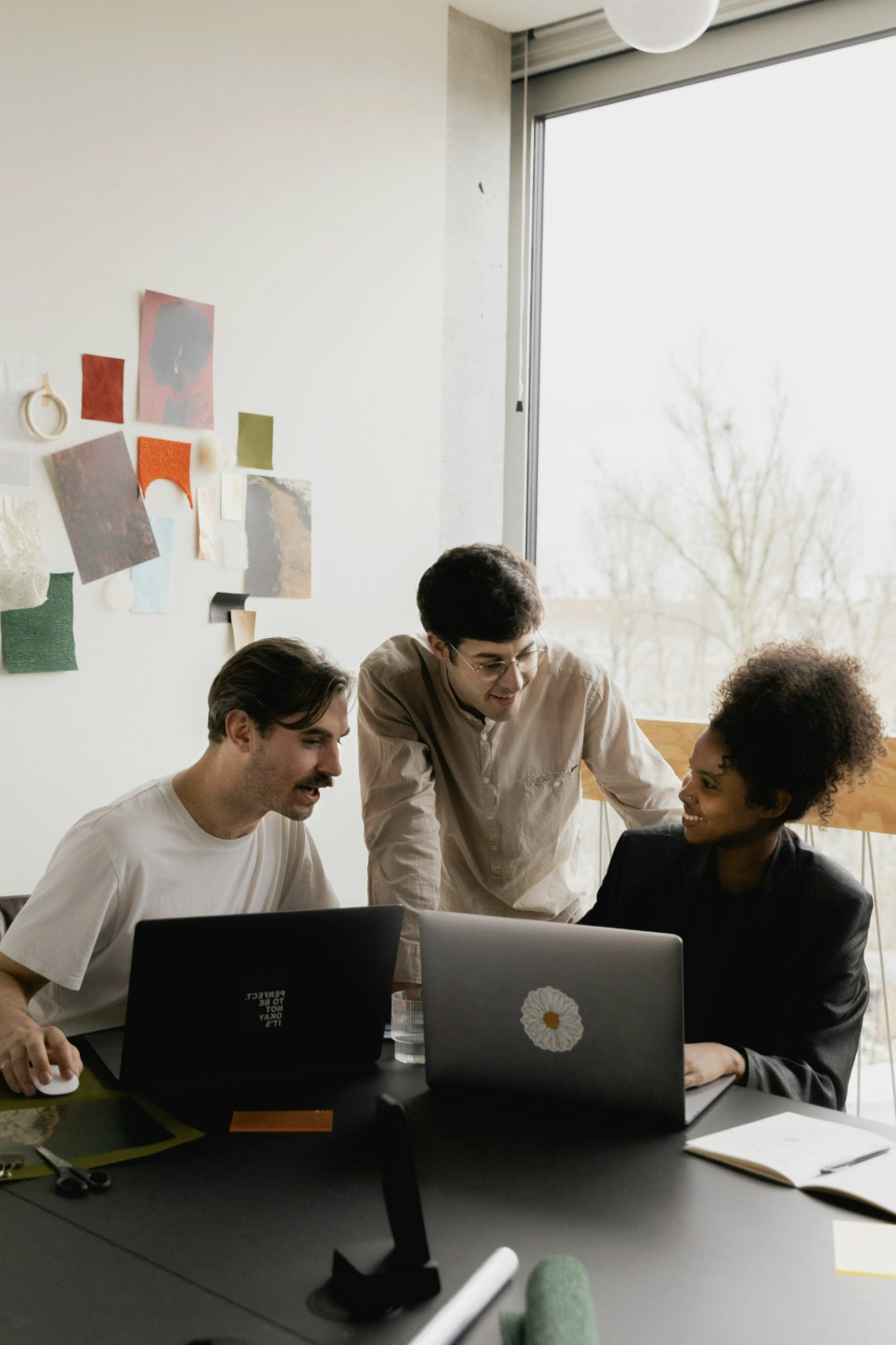 Three people discussing a website together while working on laptops.