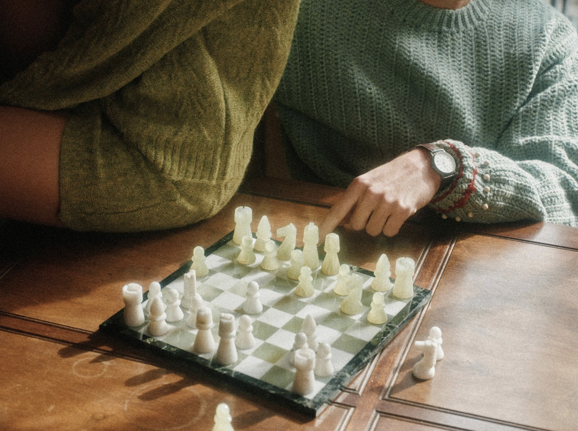 A person moving a white chess piece during a strategy game.