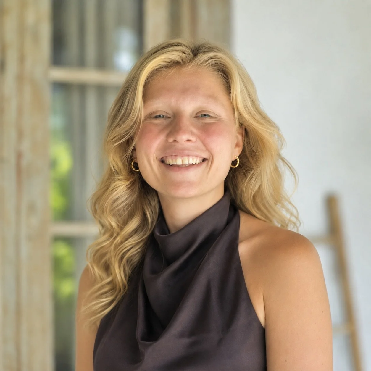 Ava Haag, founder of The Femme Explorer Studio, smiling indoors.