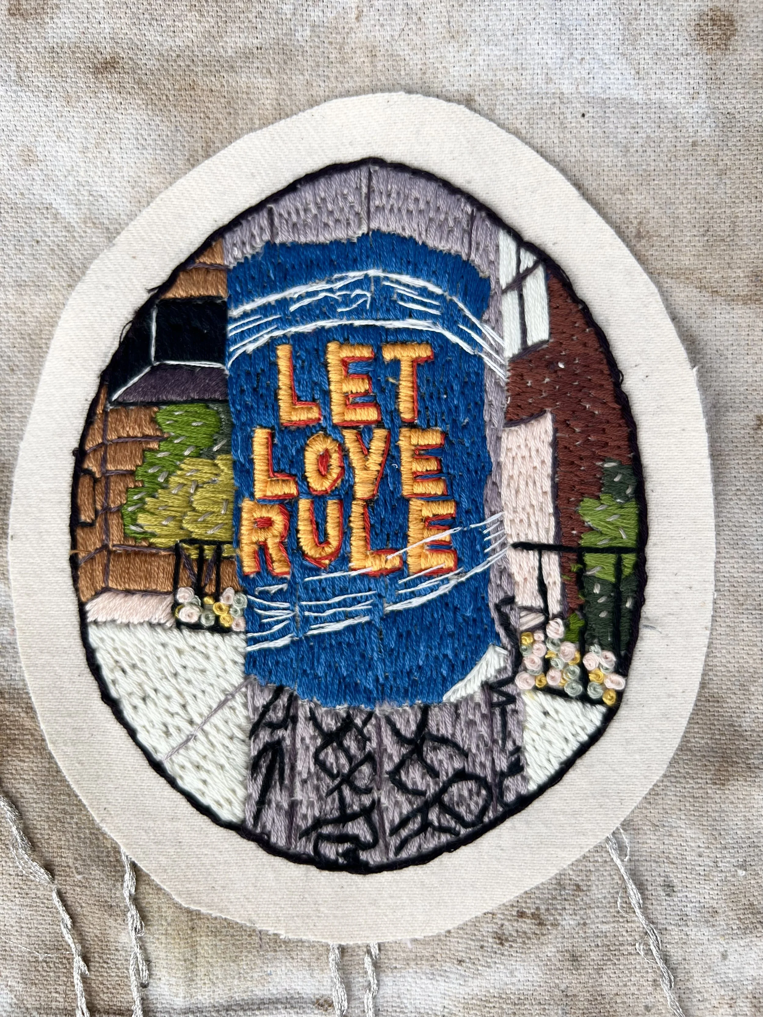 close-up of Let Love Rule hand-embroidered patch showing detailed stitching and text, designed as a wearable personal mantra.