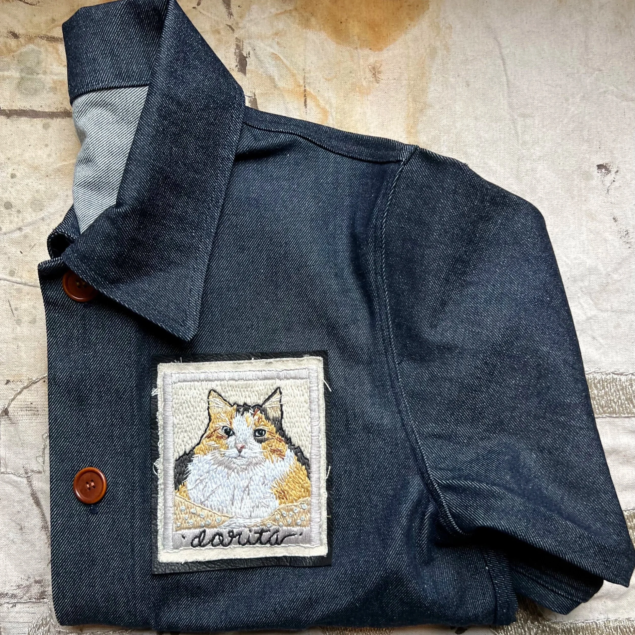 Custom modern portrait of a fluffy cat, fully stitched by hand on a contemporary denim jacket.