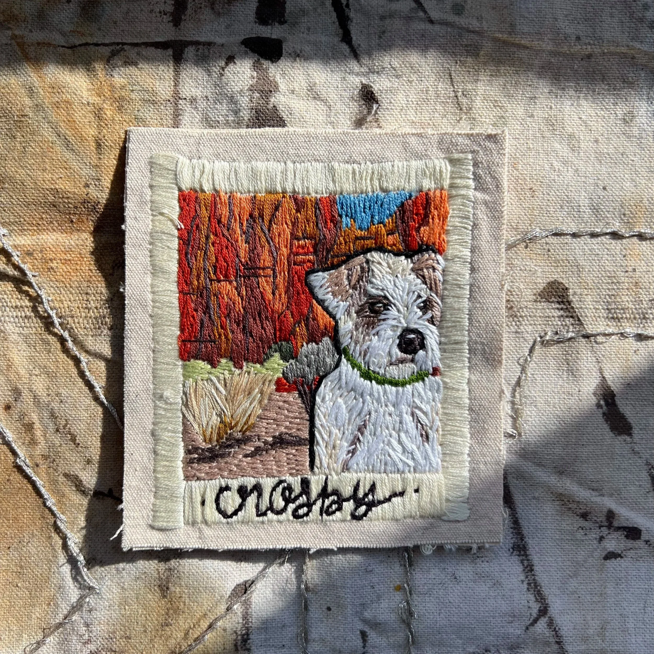 hand-stitched portrait of Crosby the white dog, set in a red rocks inspired landscape. This artistic textile becomes snapshot from a trip with your loved one.