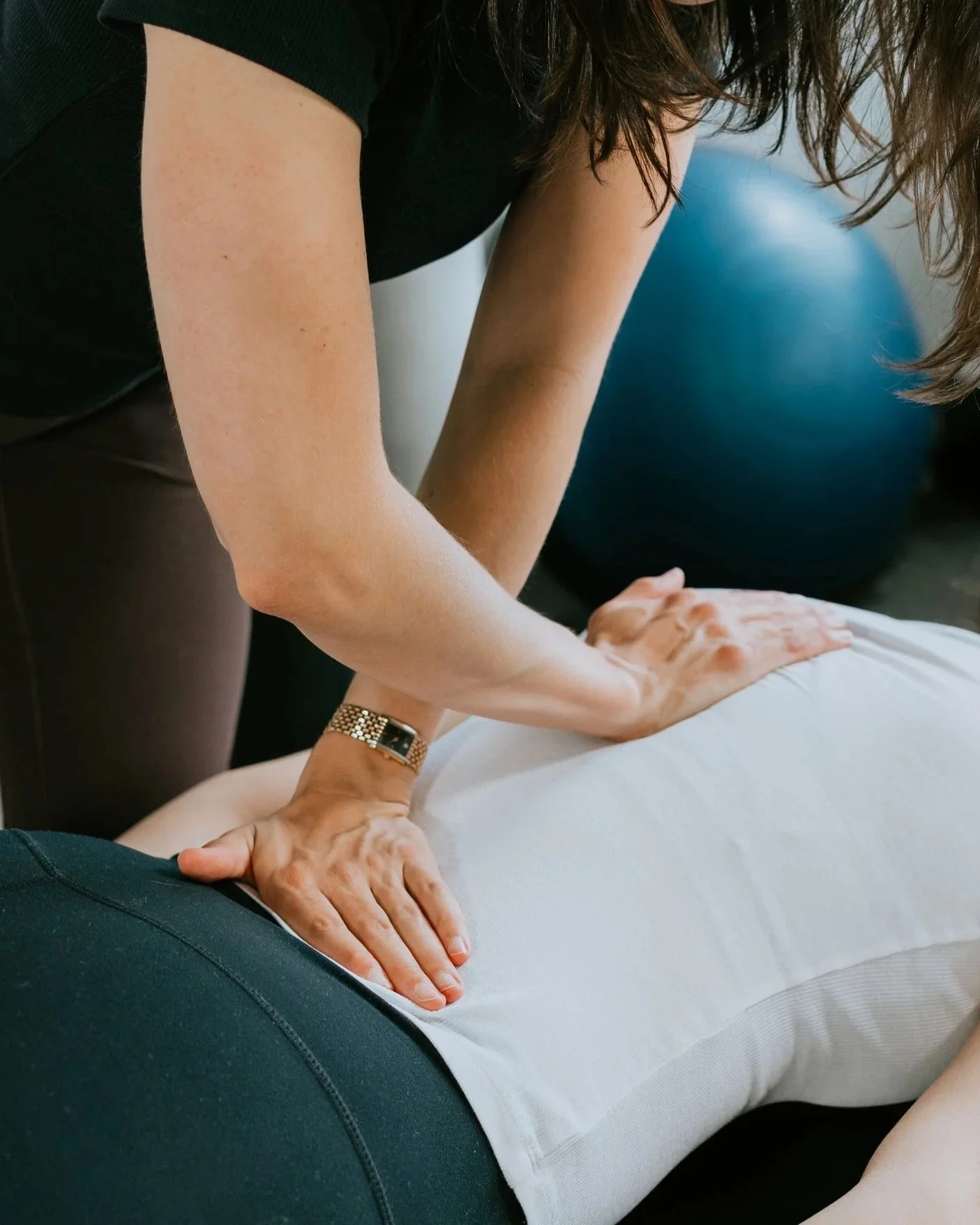 A person giving a massage to another person lying face down, with their hands on the person's back, in a chiropractic or massage setting.