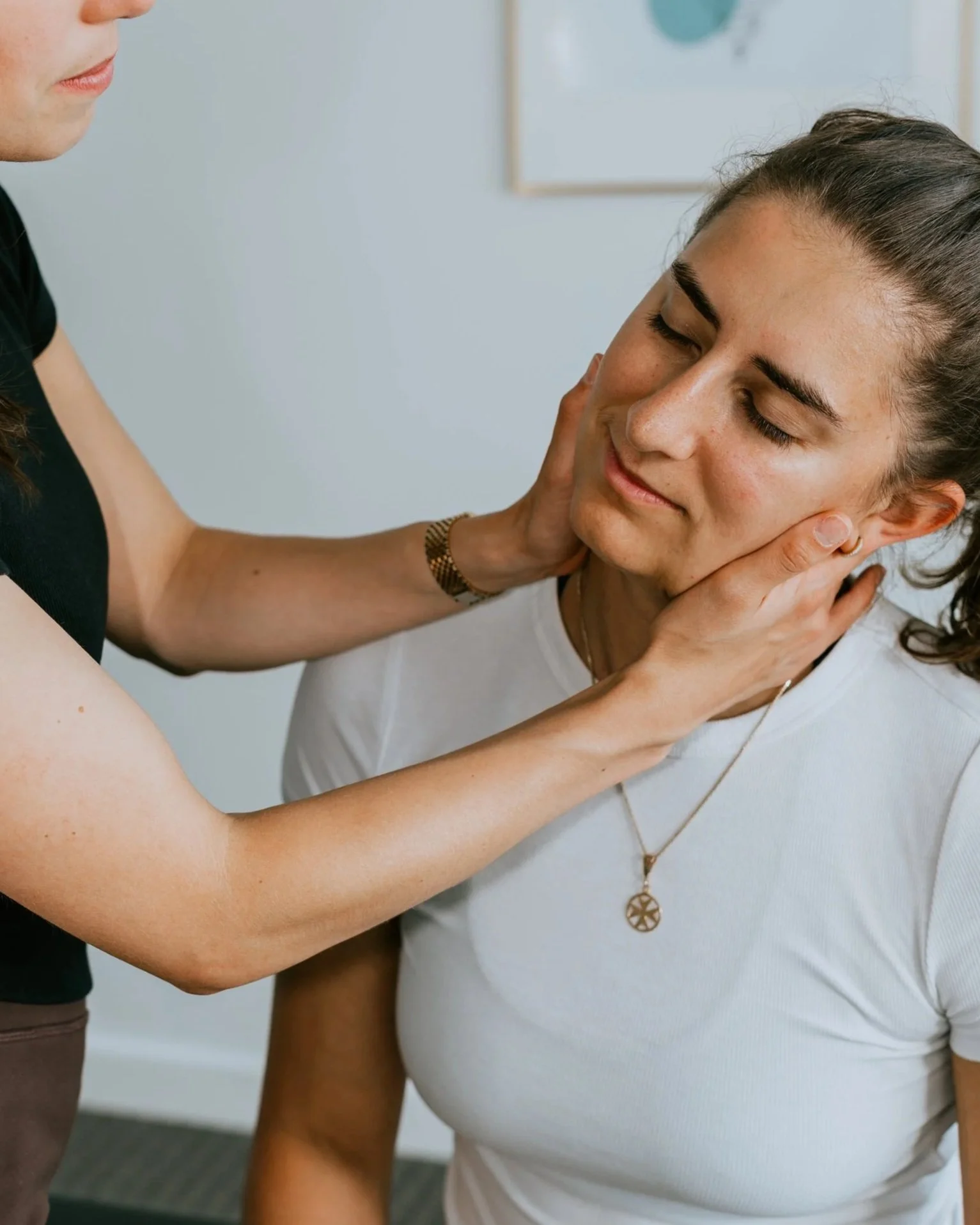 A woman gently holds a young woman's face during a comforting or healing session.