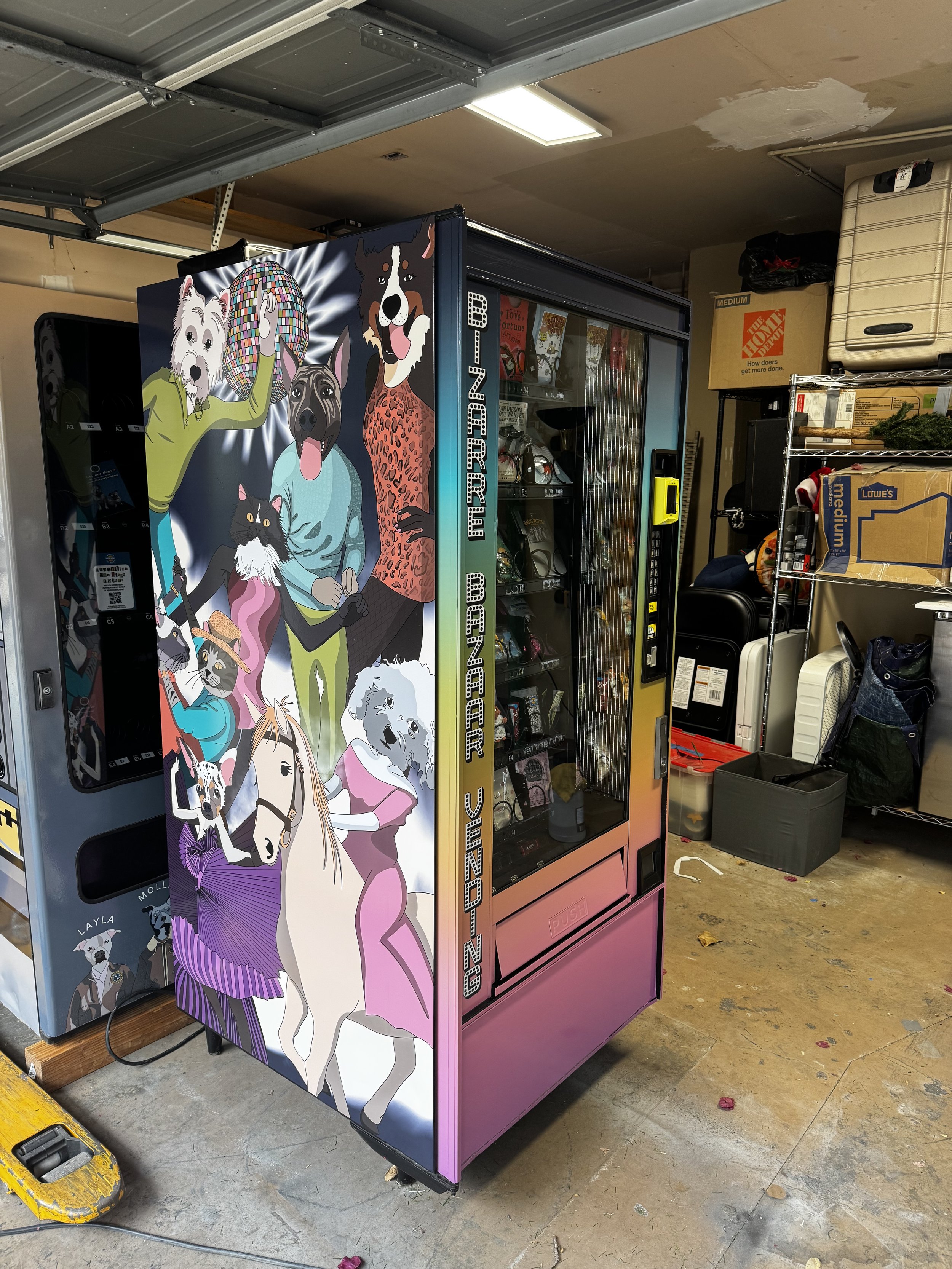 A claw machine decorated with colorful cartoon dogs and a cat, labeled 'Bizarre Bazaar Vending'.