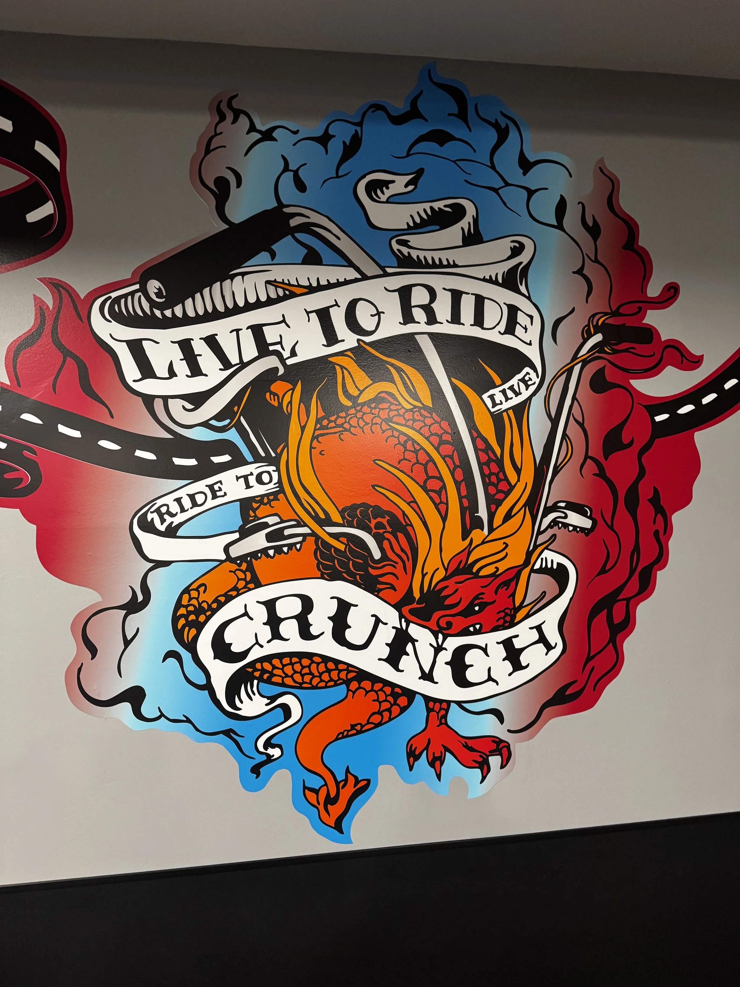A graphic mural of a dragon with motivational text: "Live to Ride, Ride to Live, Crush".