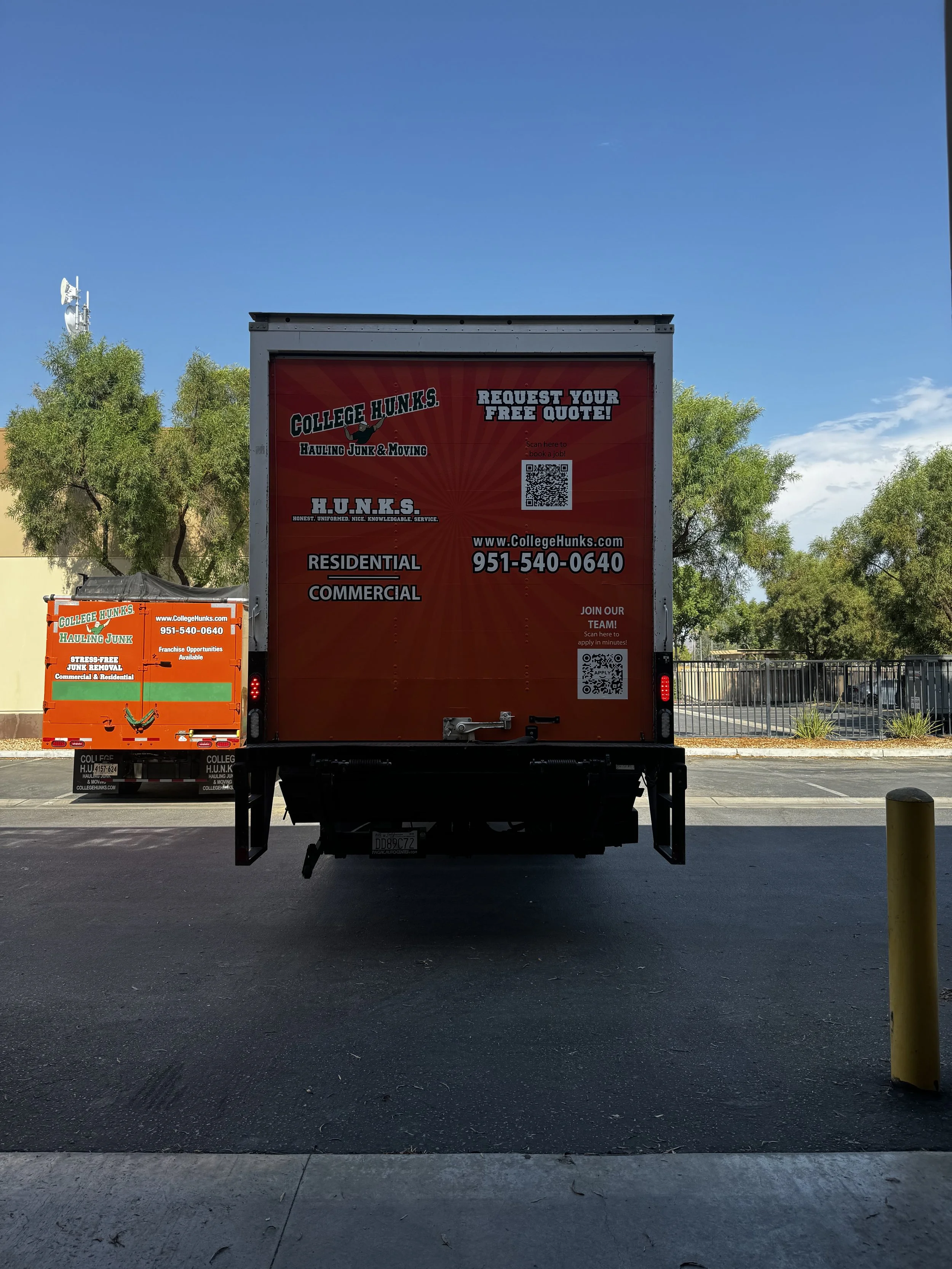 Red and black College Hunks hauling junk and moving truck with contact information, social media QR codes, and service details parked outdoors.