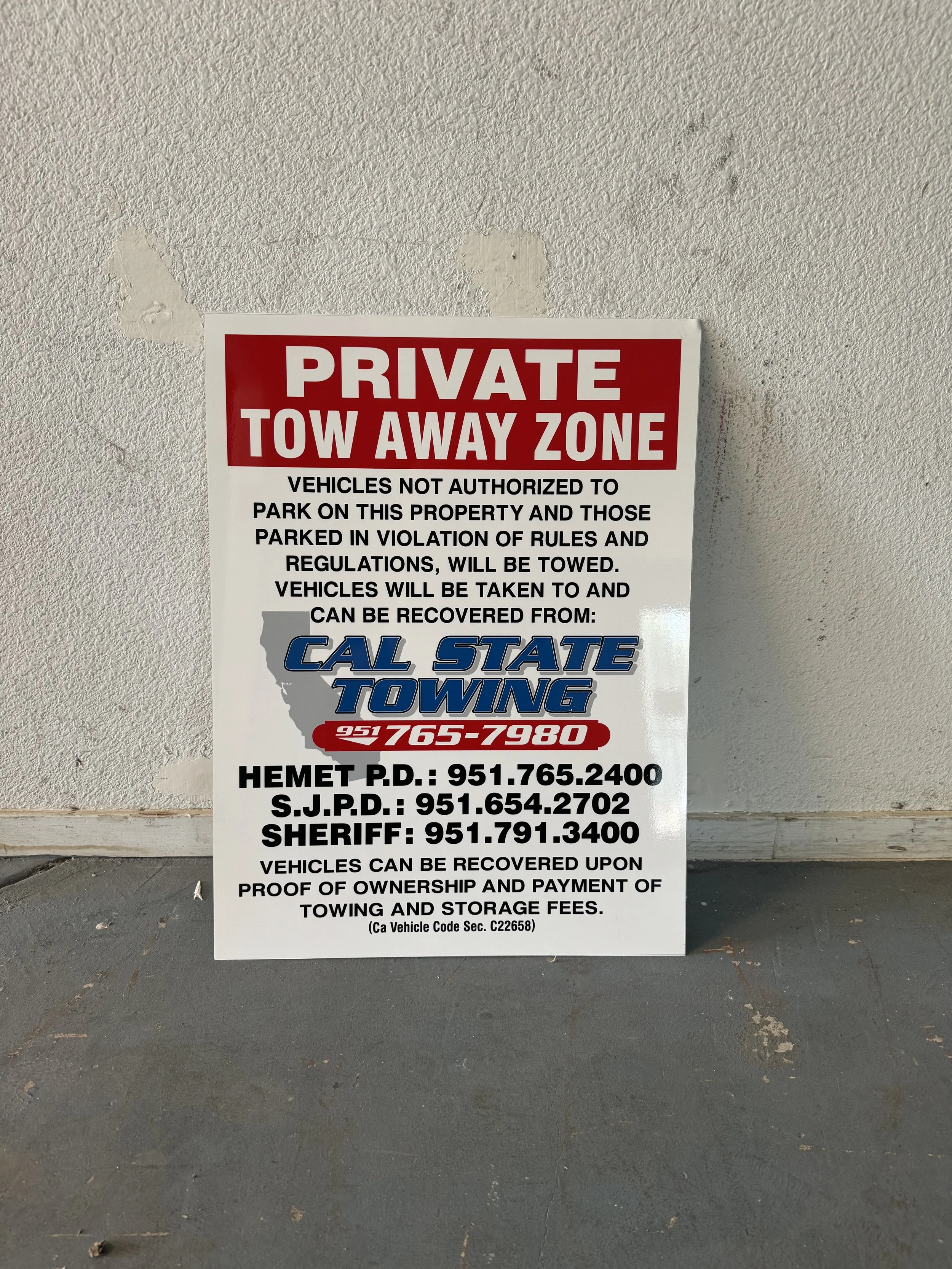 A sign on a wall that reads 'Private Tow Away Zone. Vehicles not authorized to park on this property and those parked in violation of rules and regulations, will be towed. Vehicles will be taken to and can be recovered from: Cal State Towing. Phone n
