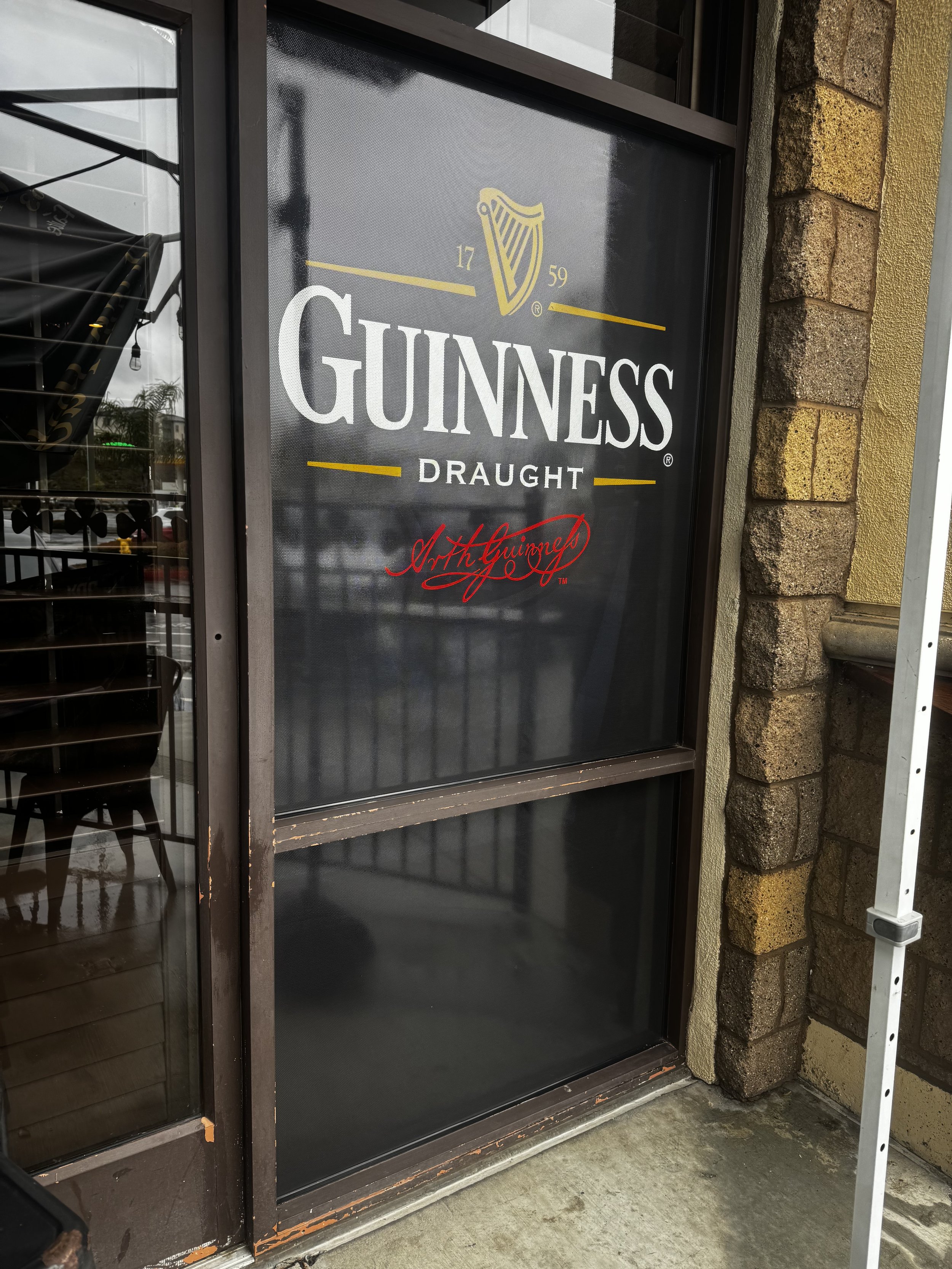 Exterior window sign for Guinness Draught with the Guinness harp logo, the year 1759, and the phrase "Art the Guinness" in red script.