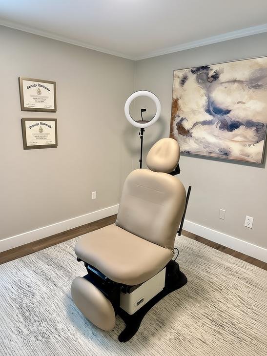 Dental examination chair in a room with gray walls, wall art, and framed certificates.