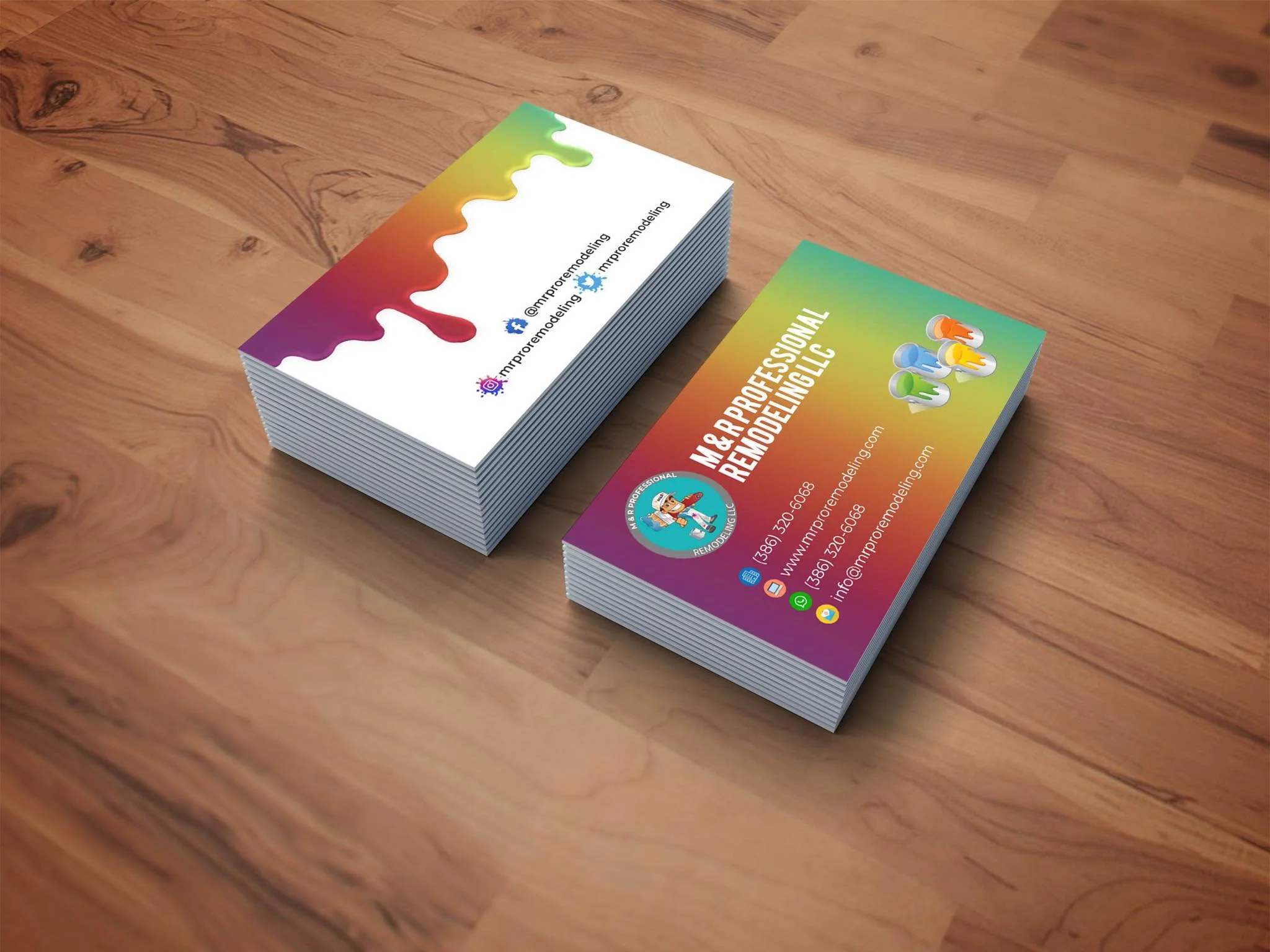 Business cards for M&R Professional Remodeling LLC featuring a rainbow-colored background, logo with a cartoon worker, and contact information including phone number, website, and email, placed on a wooden surface.