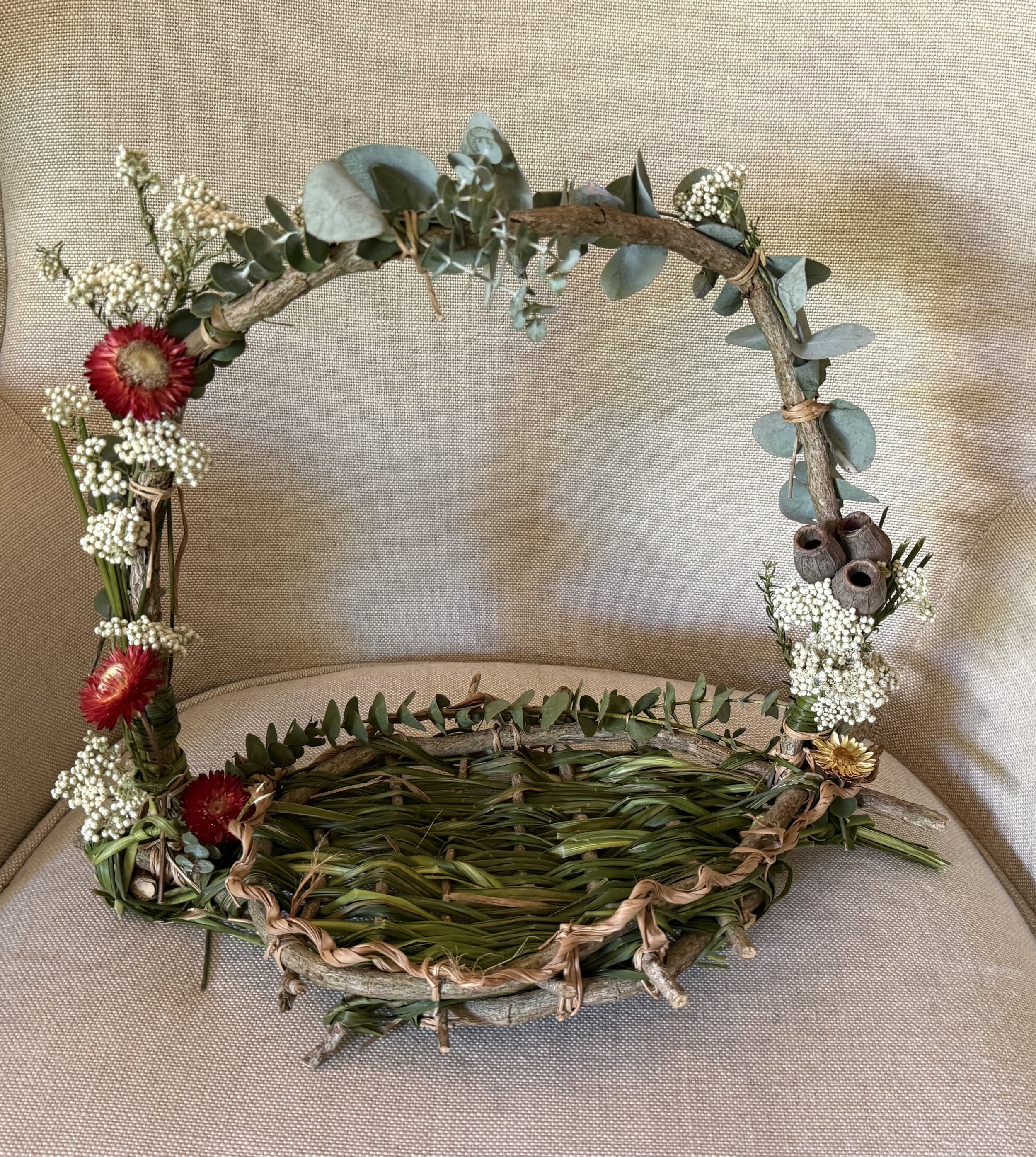 A botanical basket made by a customer at a workshop. Intertwined vine, lomandra, rice flower, gum nuts, eucalyptus leaves, ever lasting flowers.