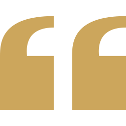 Close-up of a gold quotation mark symbol on a black background.