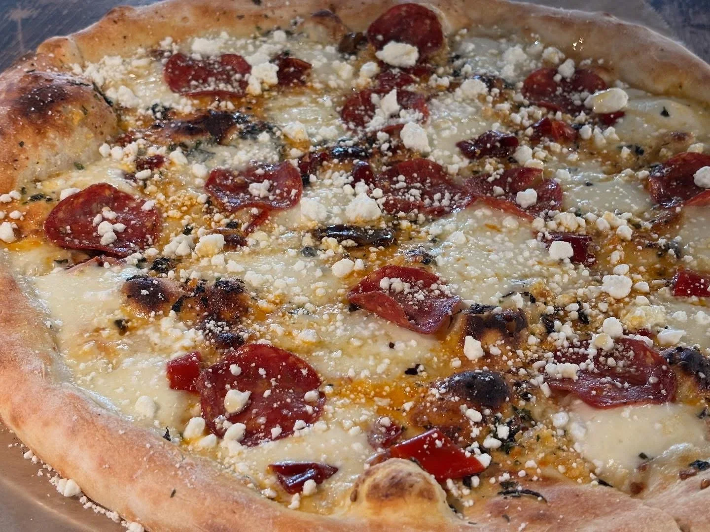 Close-up of a pizza topped with pepperoni, cheese, and crumbled blue cheese.