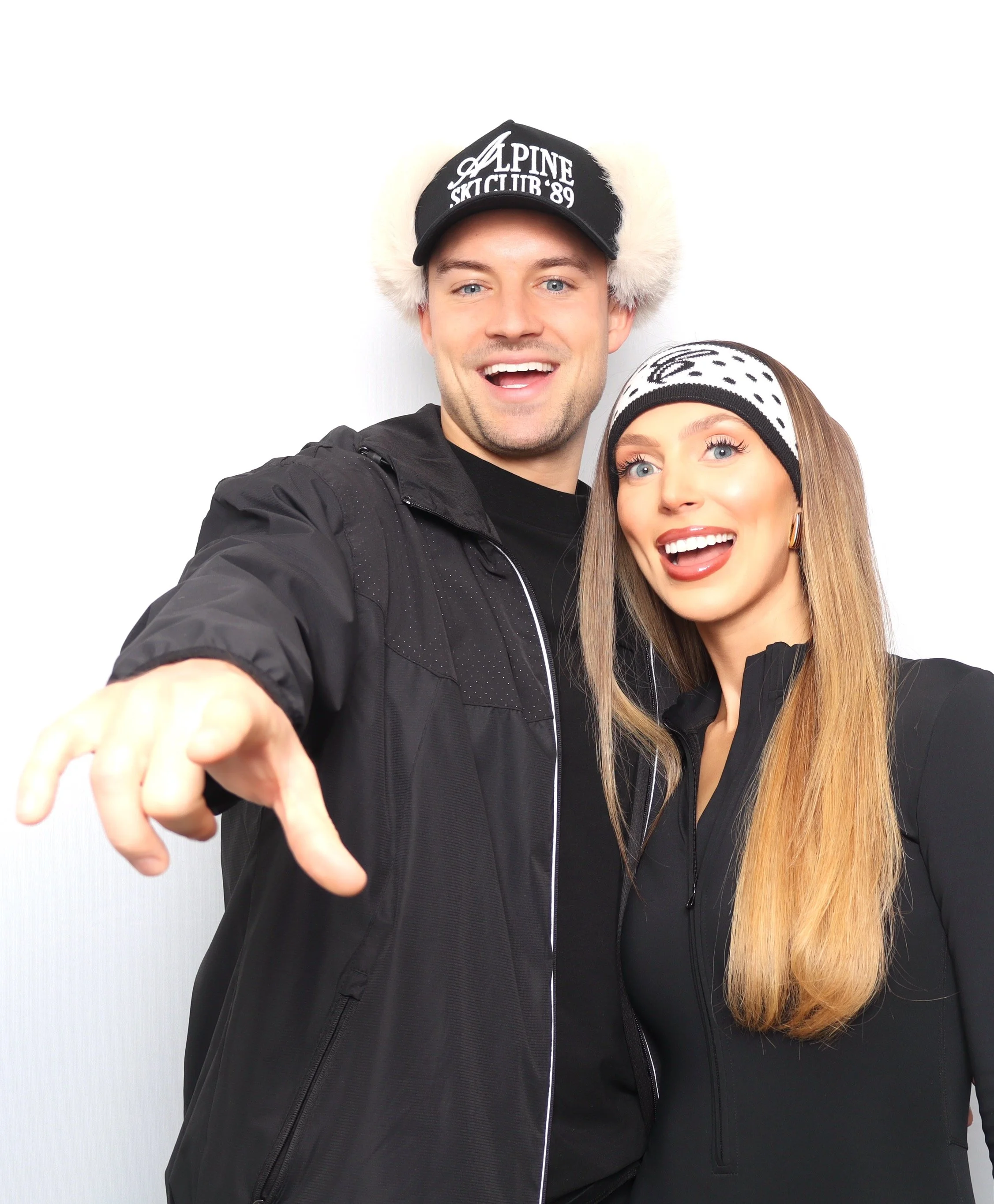 A man and woman in winter clothing and hats smiling and taking a selfie.