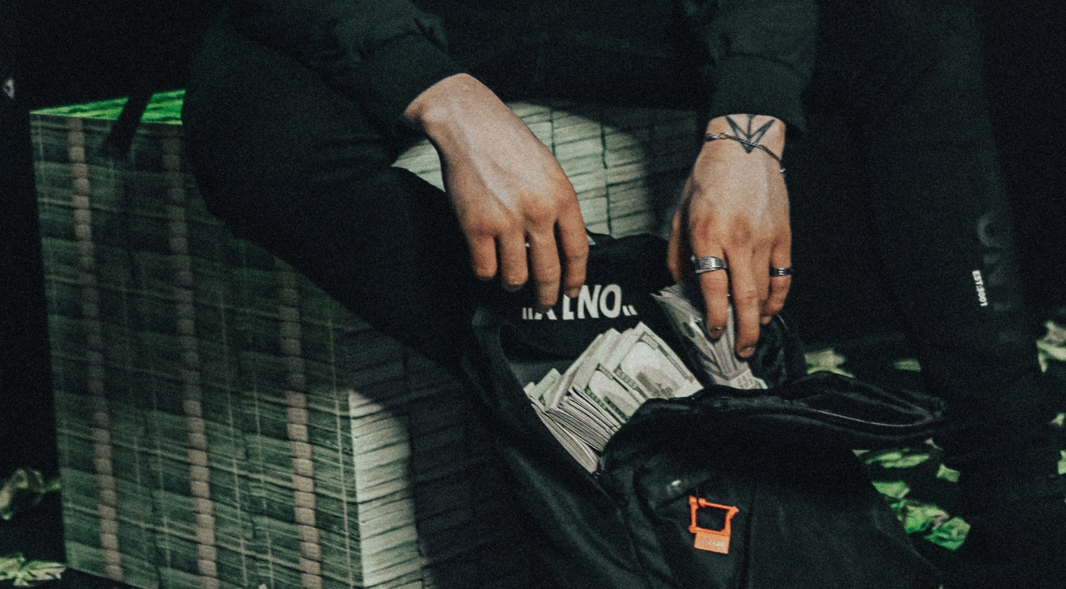 Person with multiple rings and a bracelet sitting on a bench, rummaging through a black bag filled with cash and a few credit cards free shopify dropshipping course.