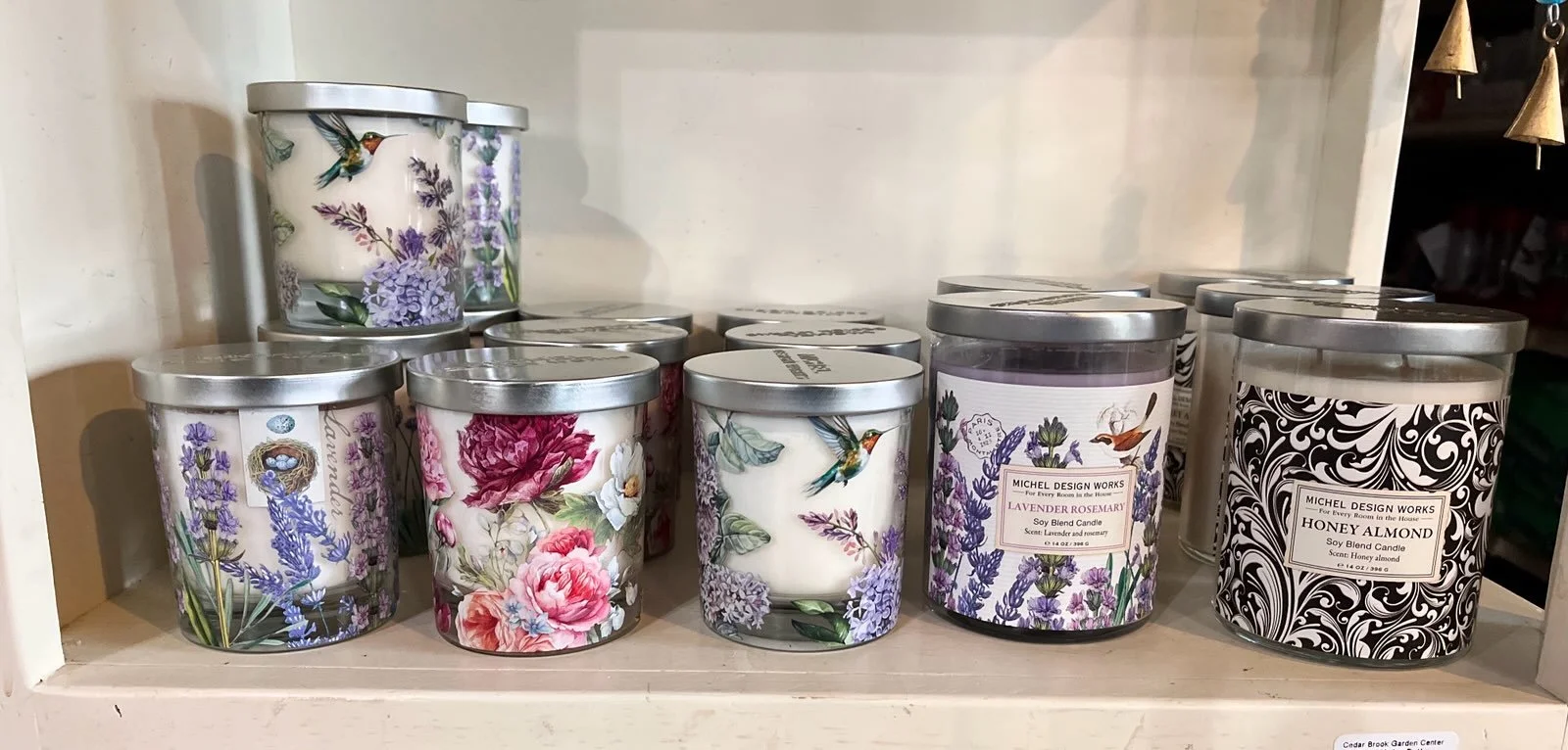Collection of scented candles with floral and nature-themed labels on a shelf.