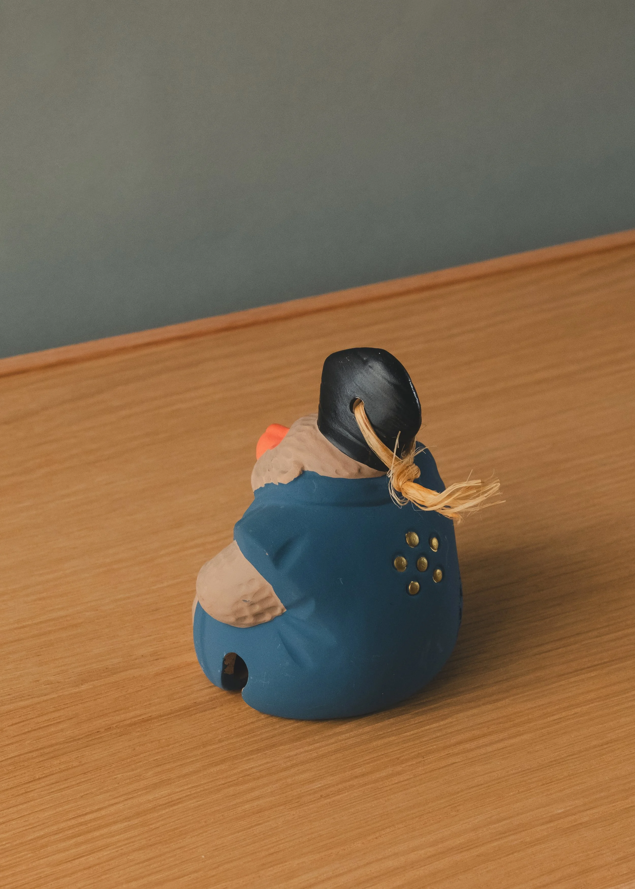 Quarter-side profile of a cerulean blue cast clay talisman. Bridging primitive Japanese folklore and minimalist interior sanctuary design aesthetics.