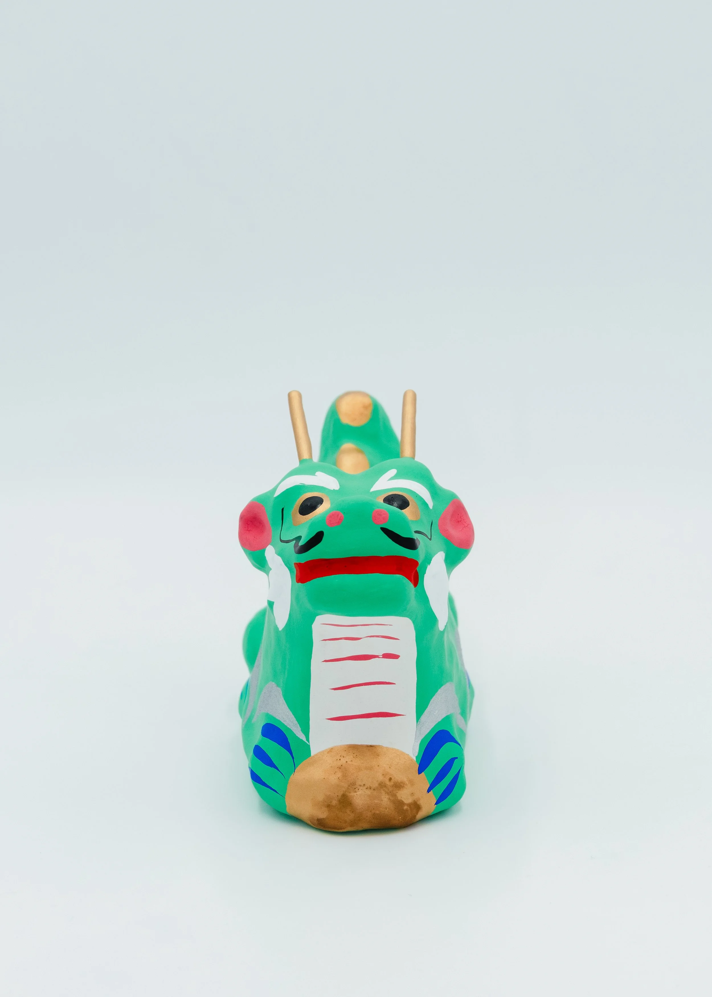 Front face of funny green dragon figurine Japanese papier-mache craft zodiac animal symbol cute expression