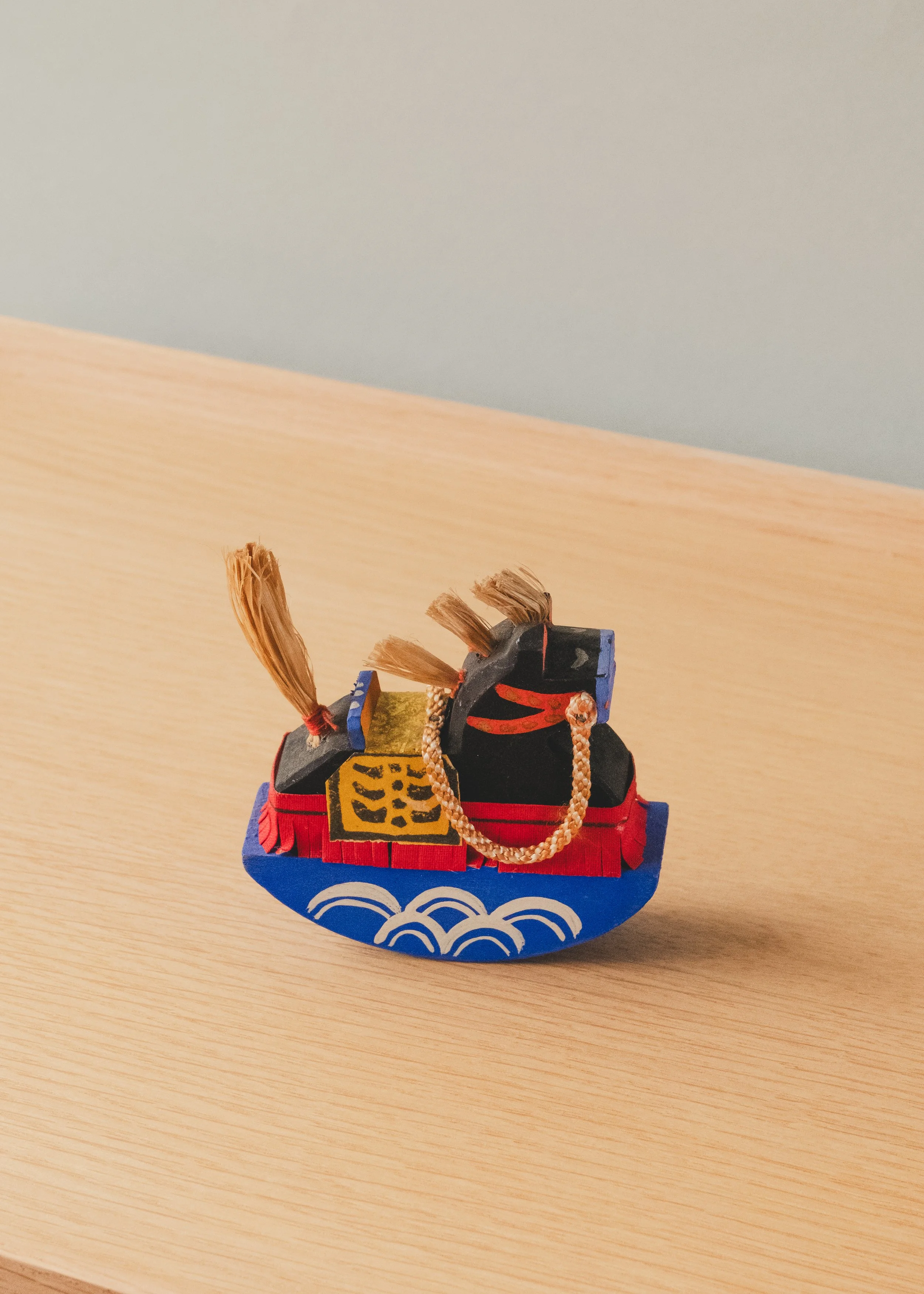 Rear perspective of THE VANGUARD STALLION 1930, a hand-carved vintage Japanese Paulownia wood horse with natural straw tail and a blue rocking pedestal.