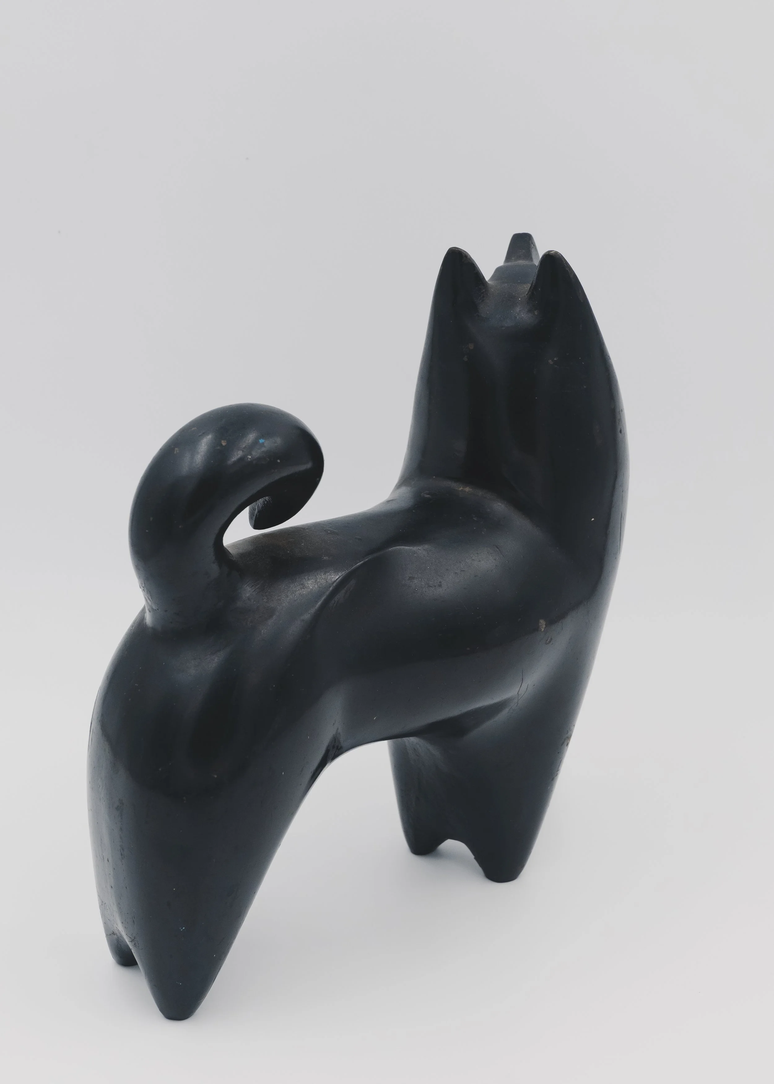 Side view of a vintage Nambu Tekki cast iron dog sculpture with a traditional curled tail (Maki-o) and nocturnal black finish, Japandi style decor.