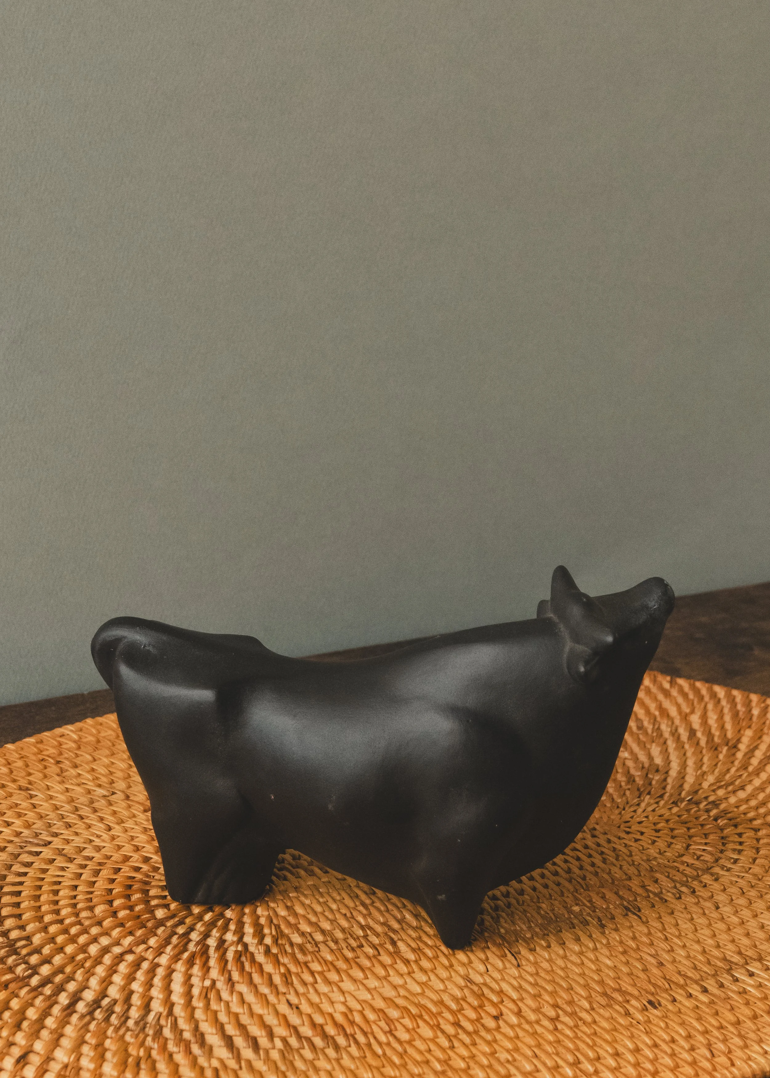 Side profile of an anonymous Japanese black bull figurine. A mid-century minimalist decor piece featuring deep, light-absorbing matte glaze and a grounded, authoritative stance.