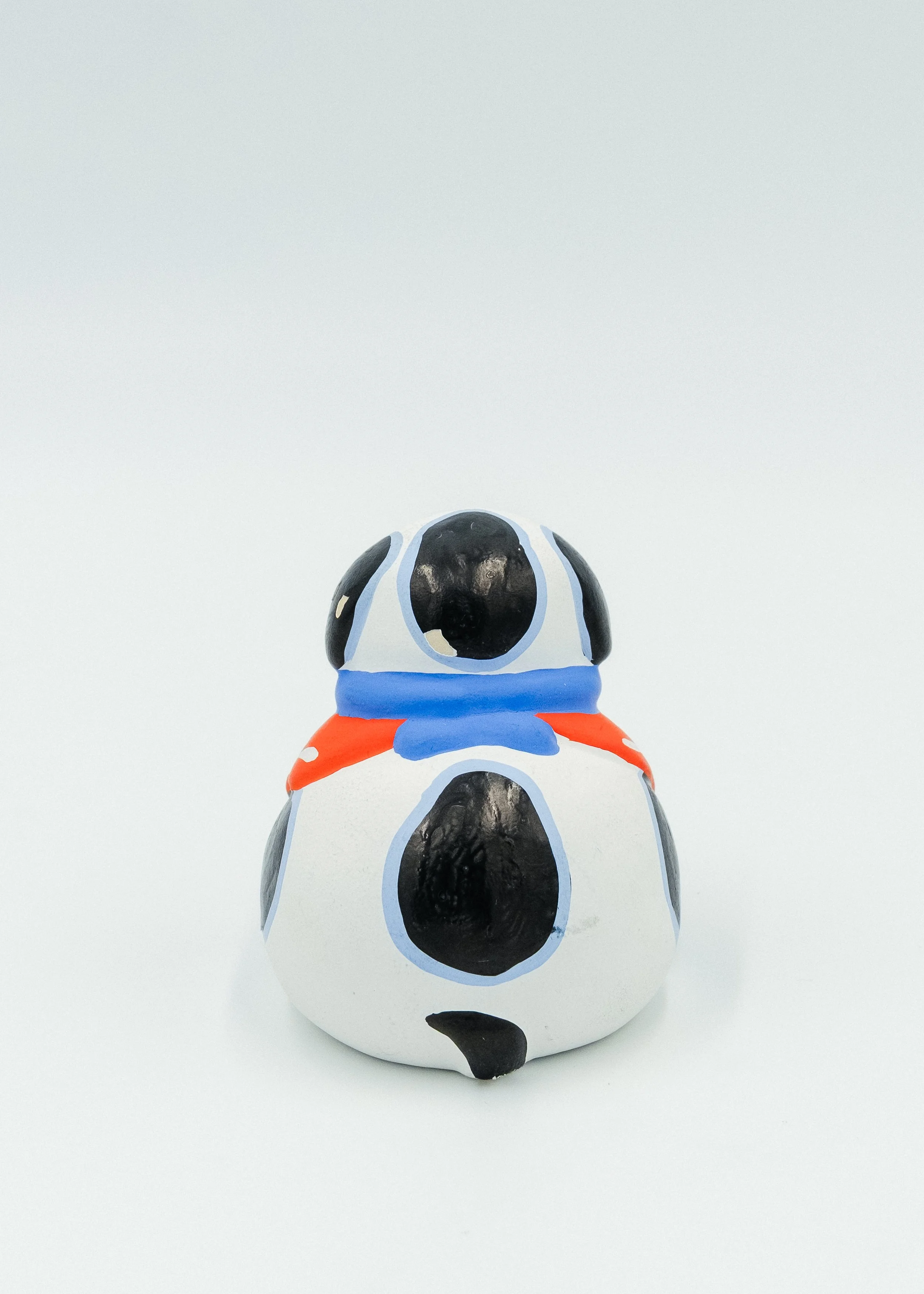 Rear view of round Japanese dog figurine Tsuchi-ningyo painted black and white folk toy Mingei decor