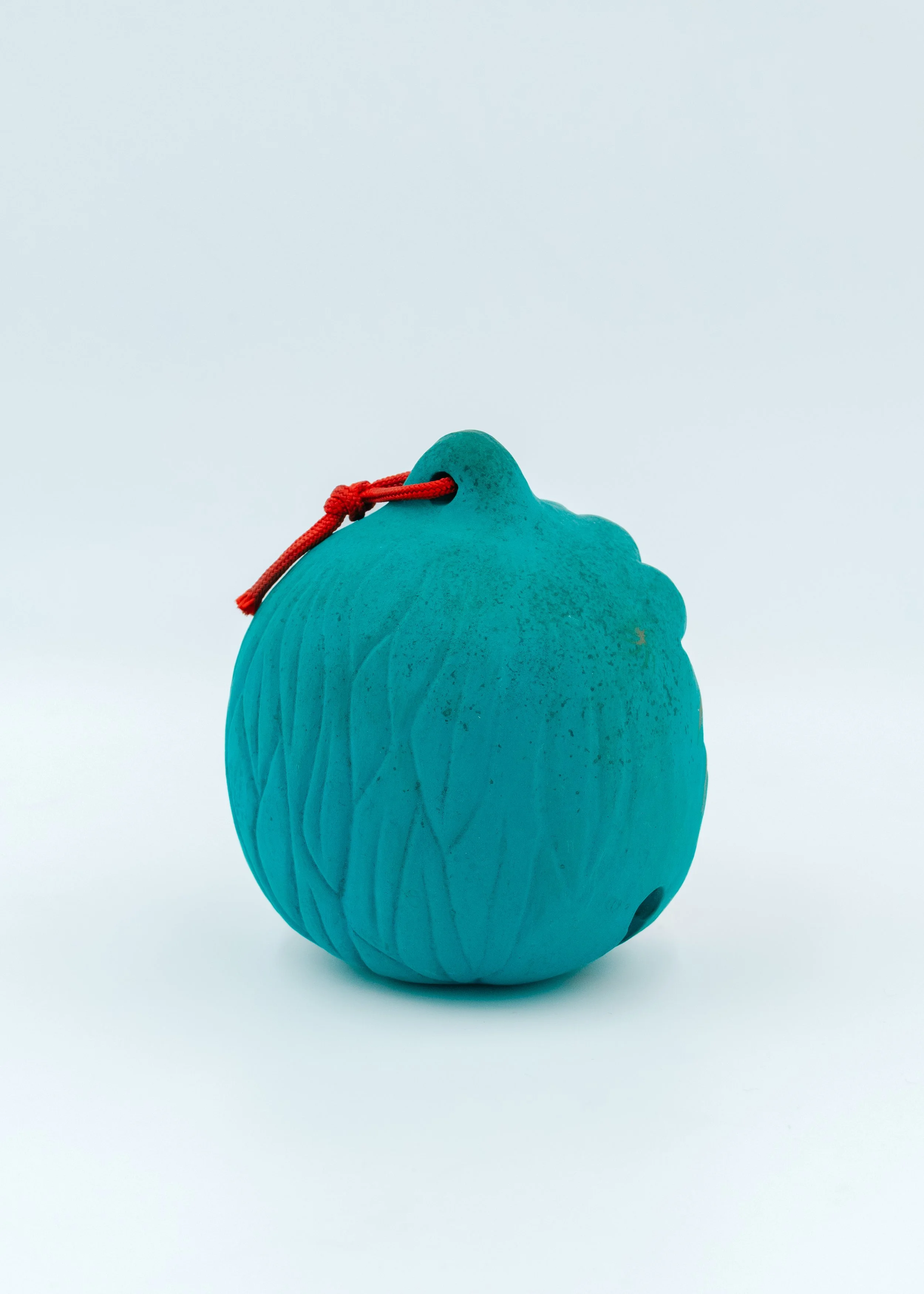 Reverse side view of a vintage Japanese turquoise clay amulet showing the textured hand-formed curves and a traditional red cord, authentic Nogomi spirit.