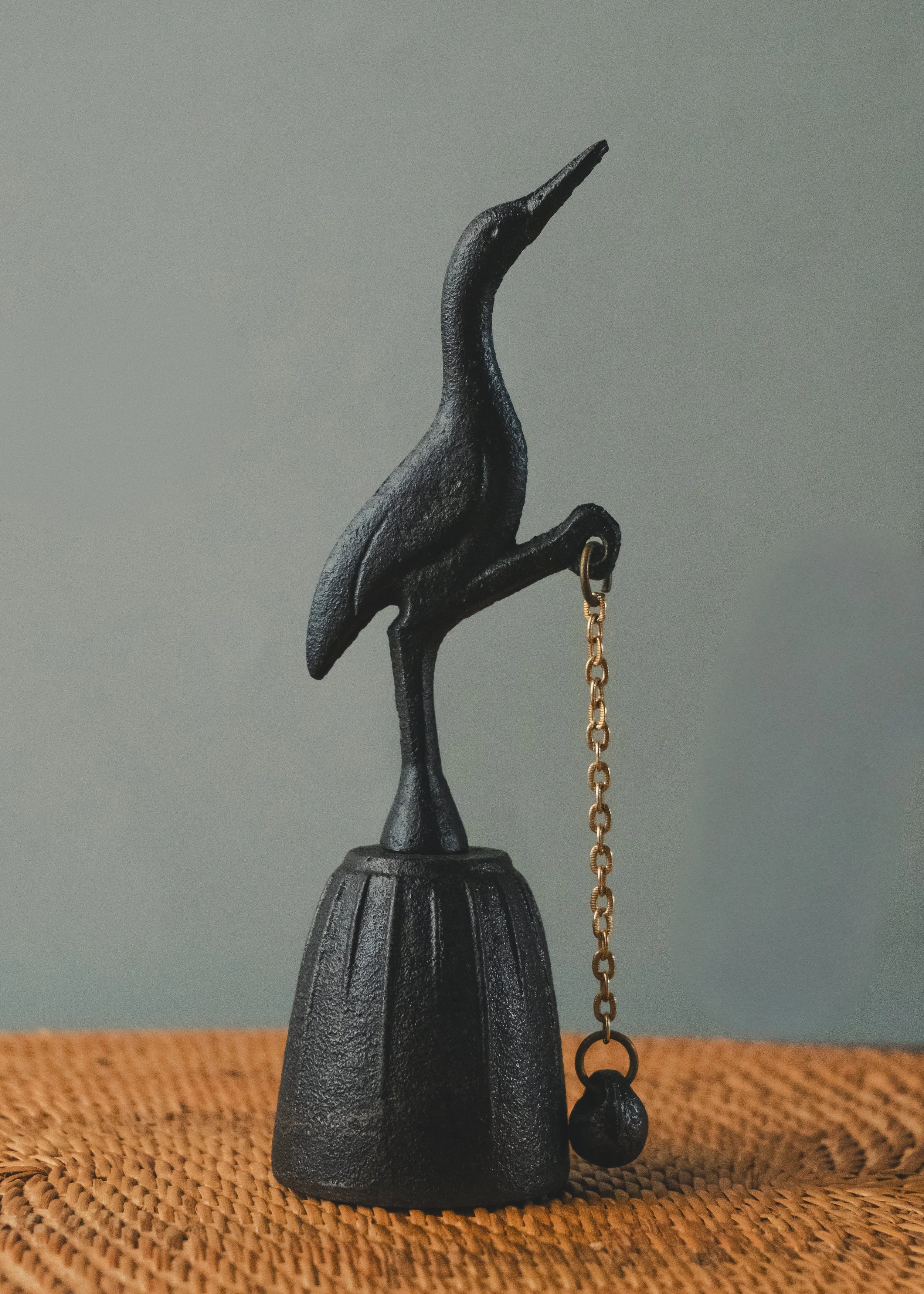 Side profile of the ARCHETYPE: CRANE BELL 1970. An anonymous Japanese iron masterpiece of a standing crane, serving as a functional sonic monument for meditation.