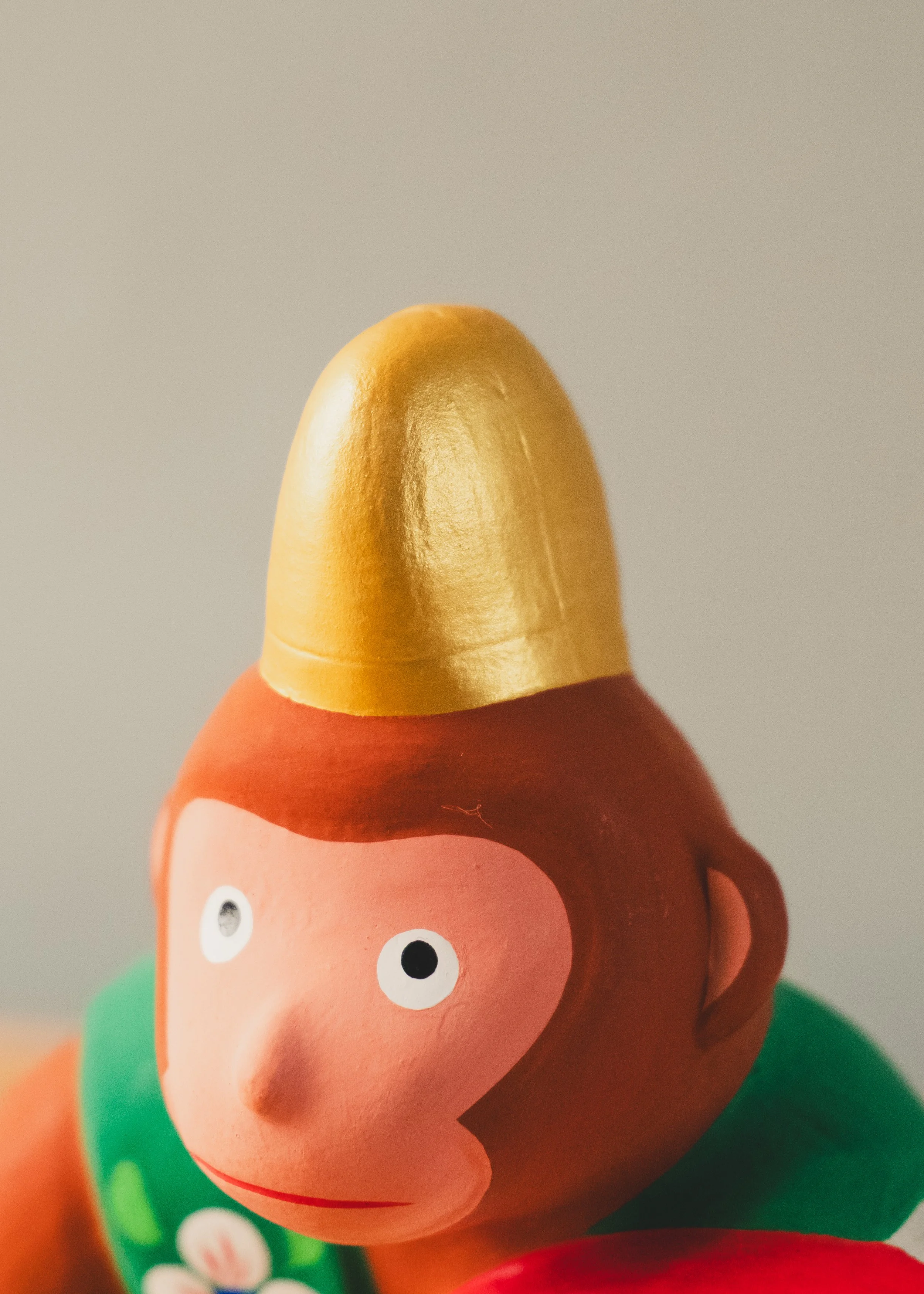 Macro detail of traditional hand-painted floral motifs on a Japanese clay monkey figurine. Evidence of the human touch in Mid-Century folk art.