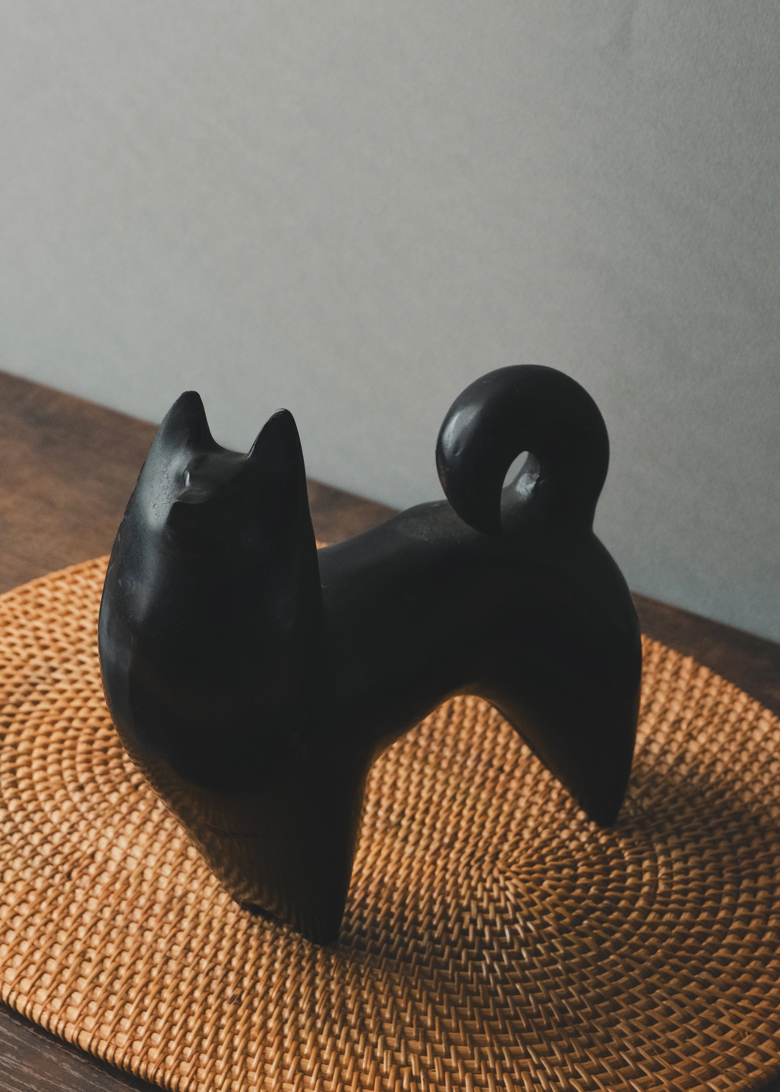 Modern minimalist Nambu Tekki iron dog figurine on a woven reed mat (tatami texture), showcasing spiritual gravity and wabi-sabi aesthetics.