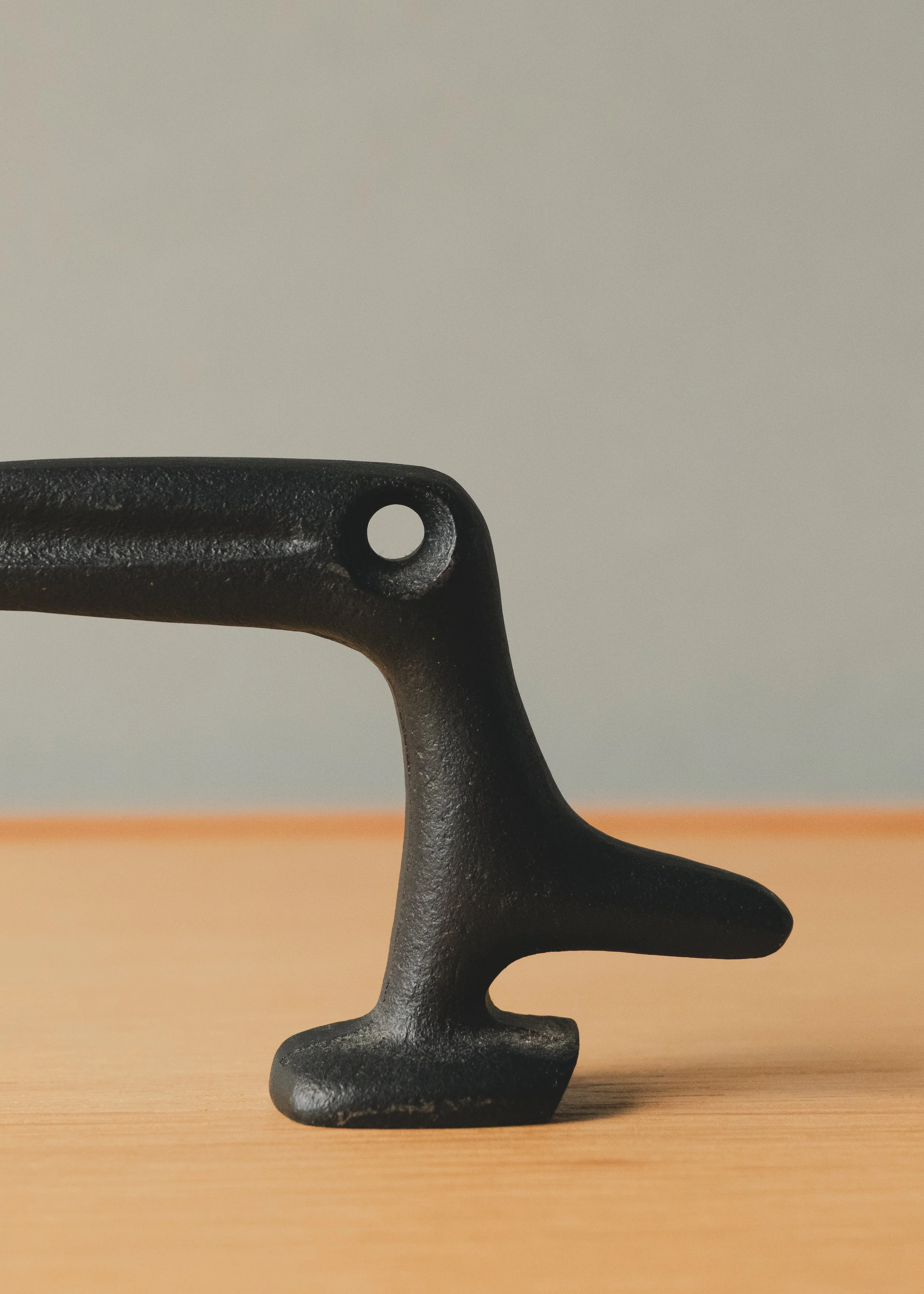 Macro shot of the raven's head and beak silhouette, highlighting the organic curves and unglazed material honesty created through traditional sand-casting techniques.