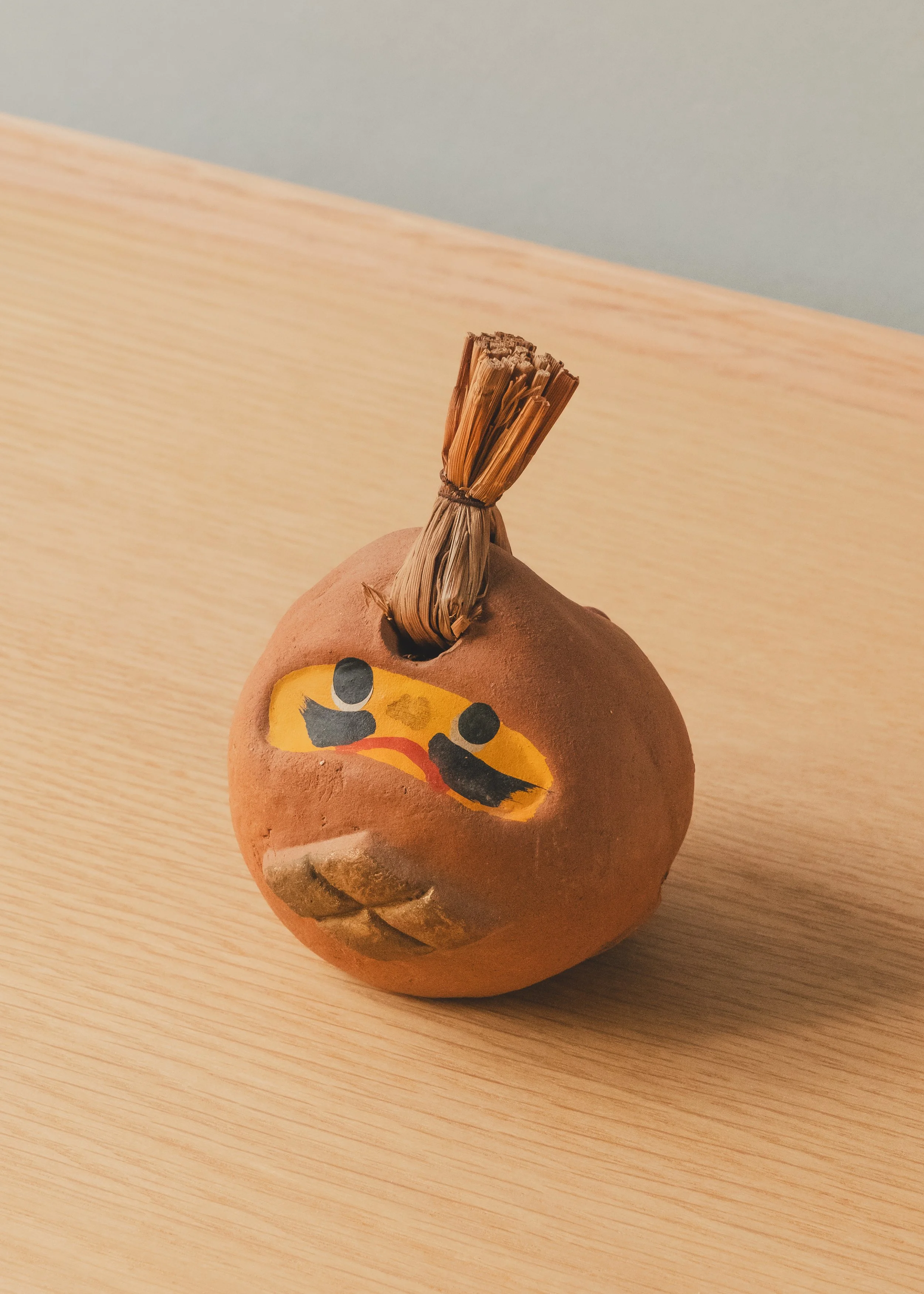 Spherical terracotta ritual talisman from Japan, showcasing the raw unglazed texture and a sacred gold diamond crest, archived by MINGEI 1926.