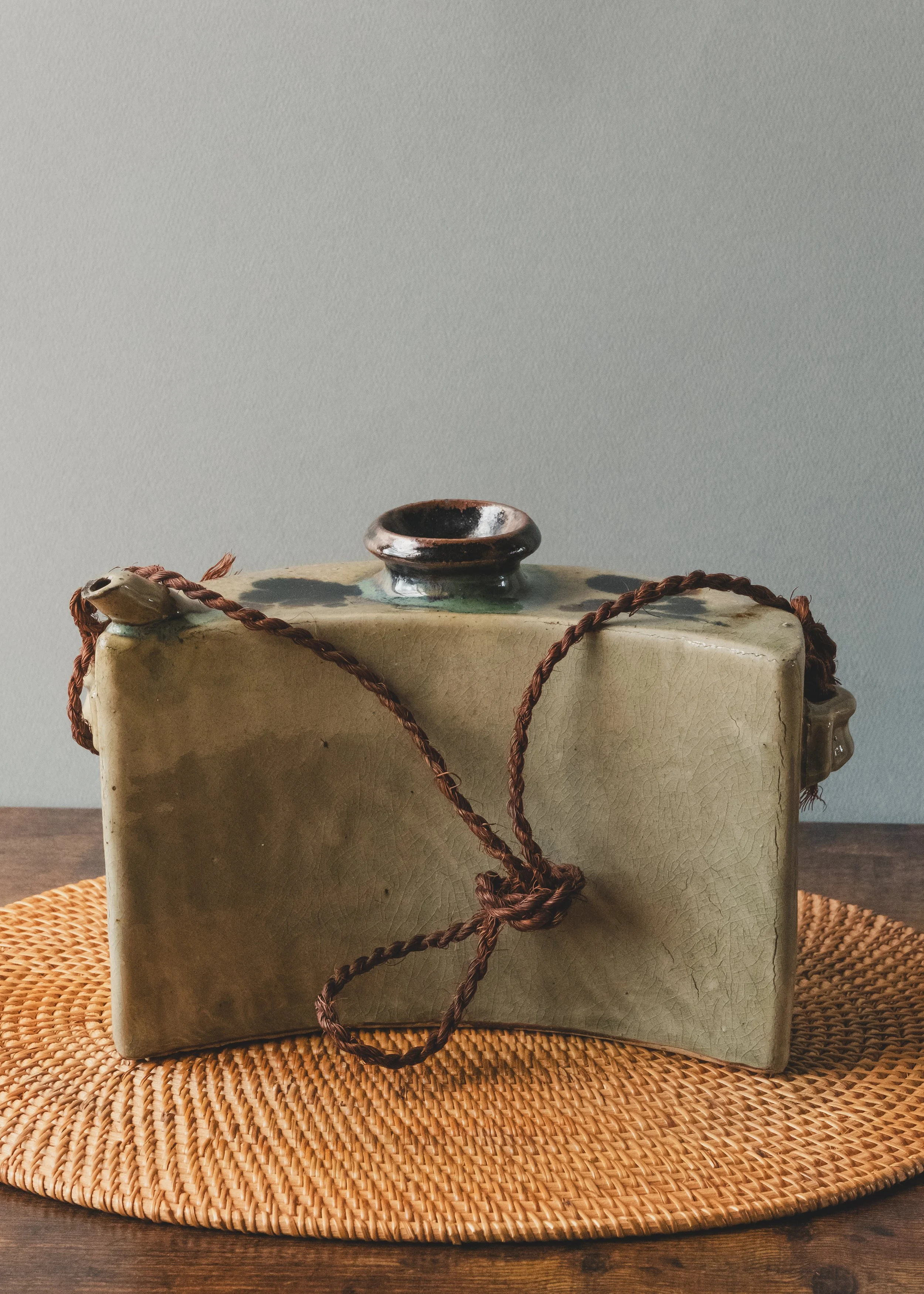 Profile view of a Japanese handmade clay bell (Tsuchi-rei) showing the ergonomic curved structure for portable use.