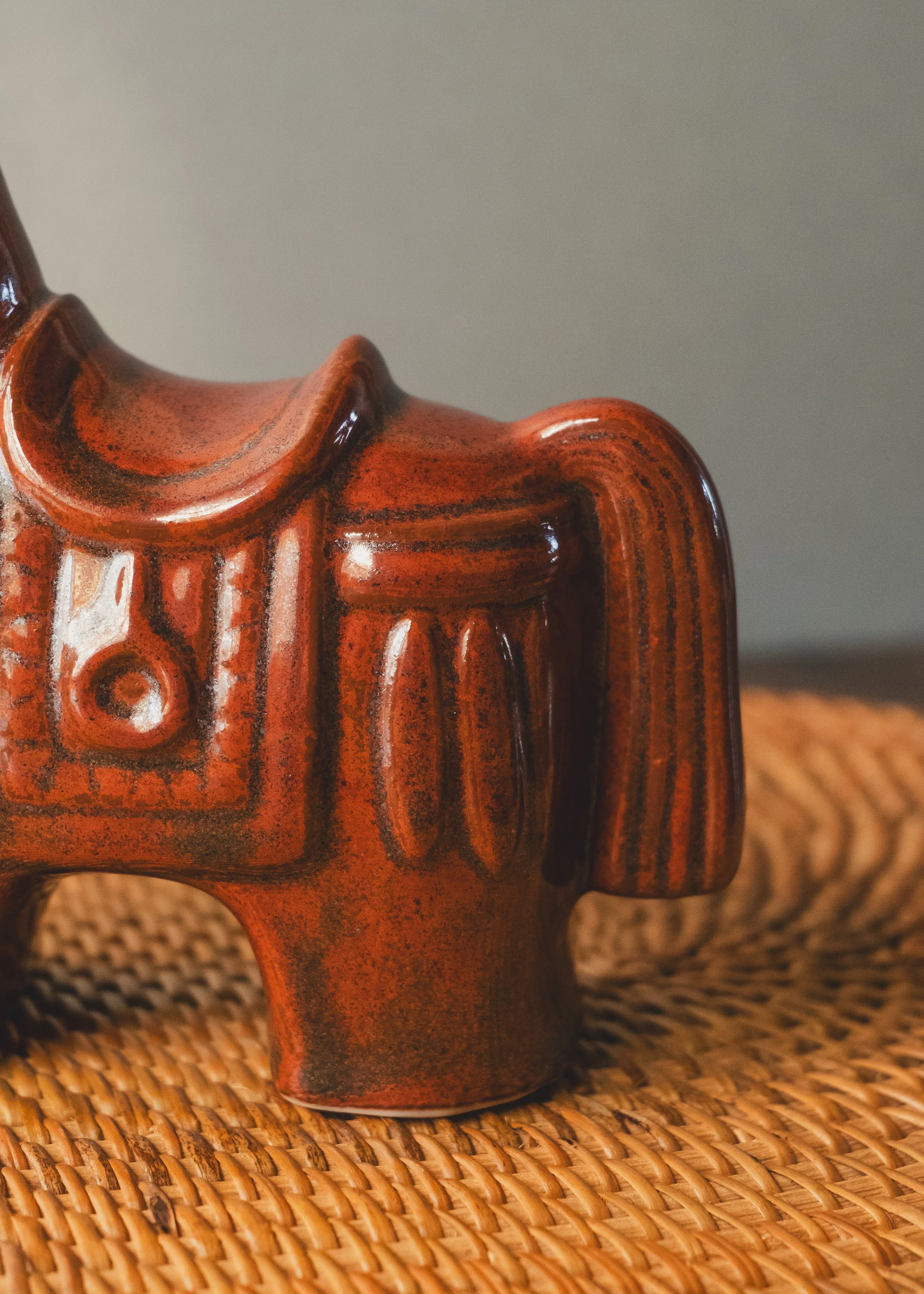 Close up detail of iron-amber glazed ceramic texture with vermilion painted accents.