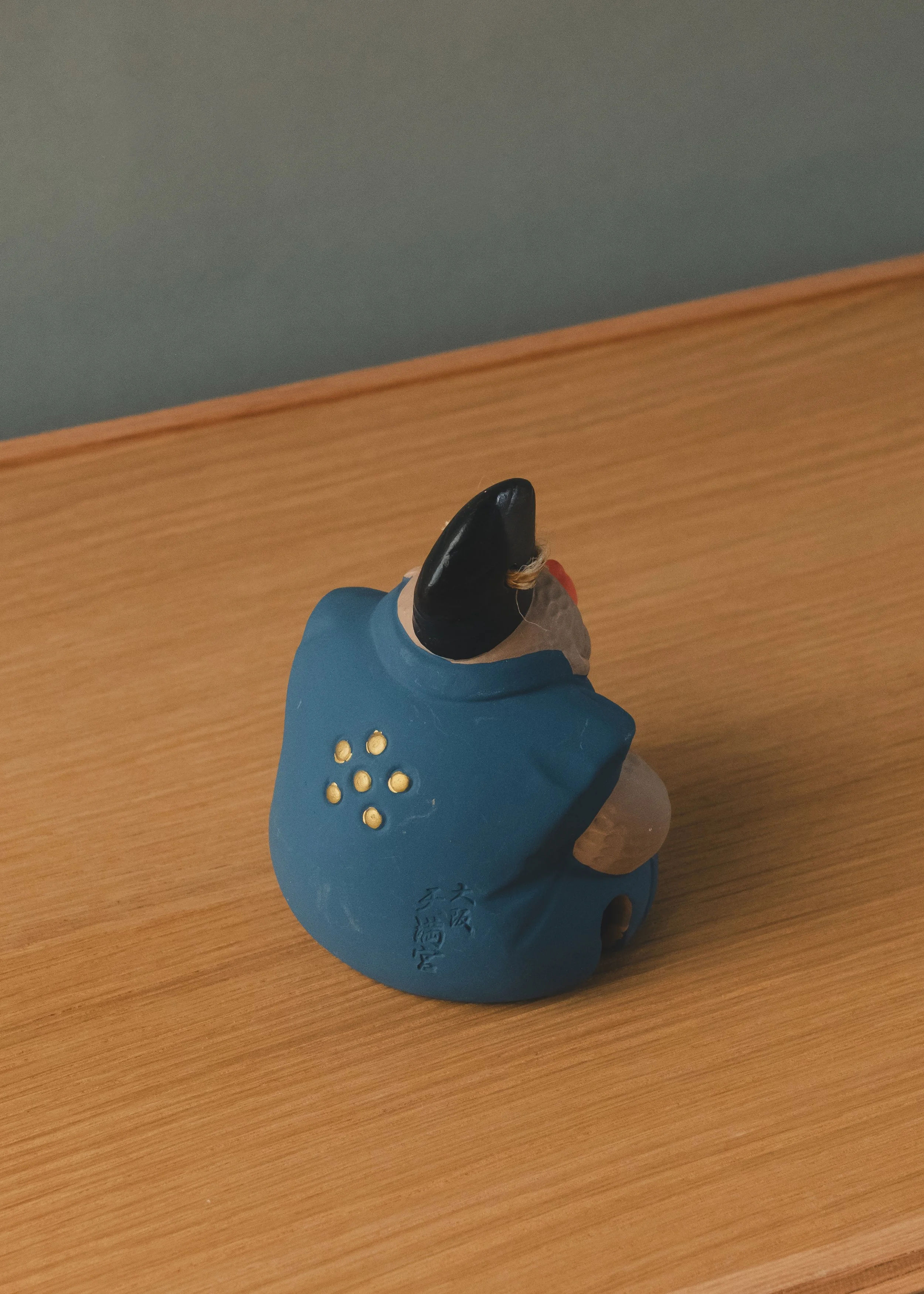 Rear view of a Japanese monkey amulet featuring the golden Ume-mon (Plum Blossom) crest of Osaka Tenmangu. An authentic specimen of Mingei folk tradition.