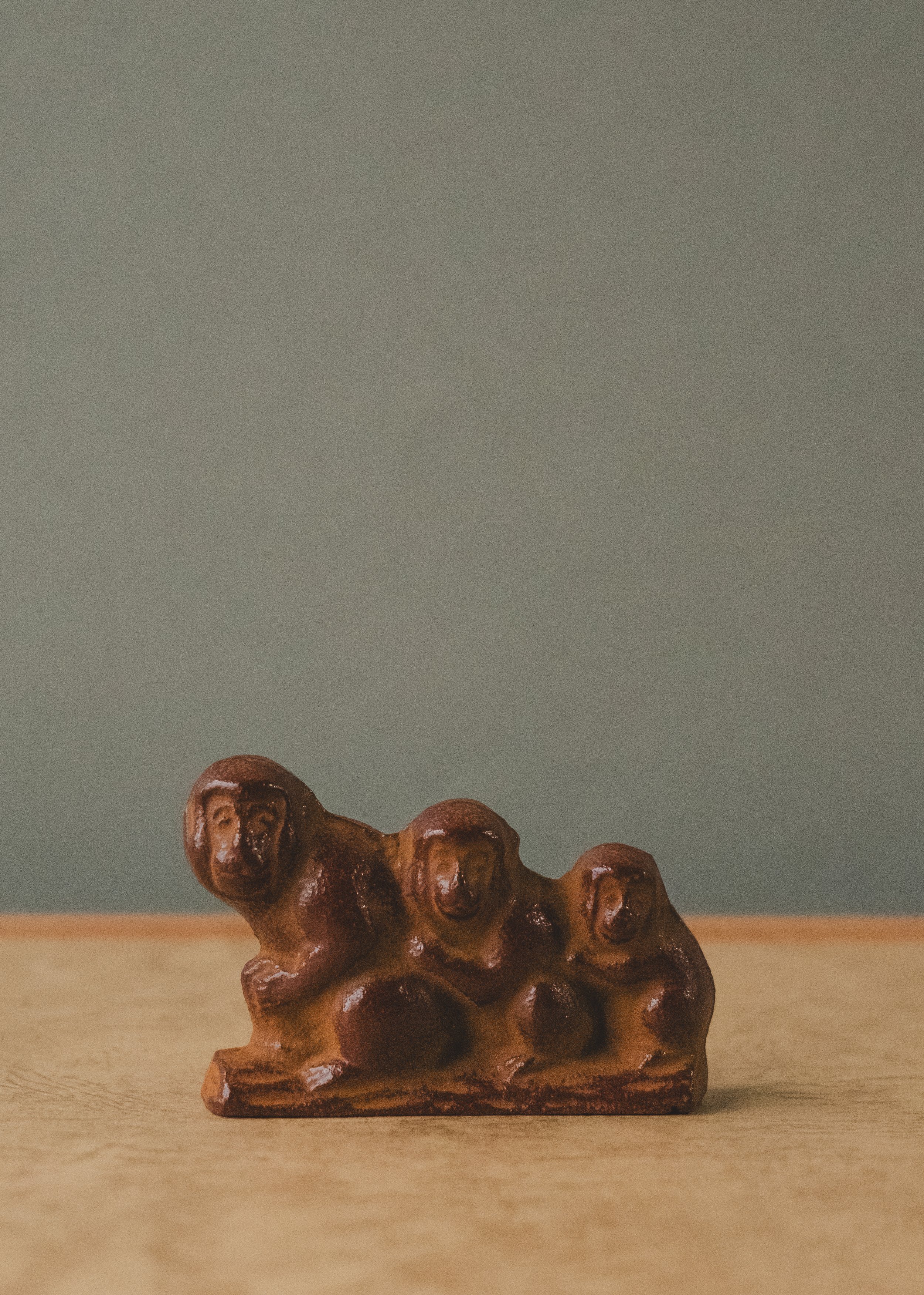 Detailed face of a Nambu iron monkey trio. Hand-lacquered 1954 Japanese artifact showcasing the raw textural grain of traditional sand-casting.