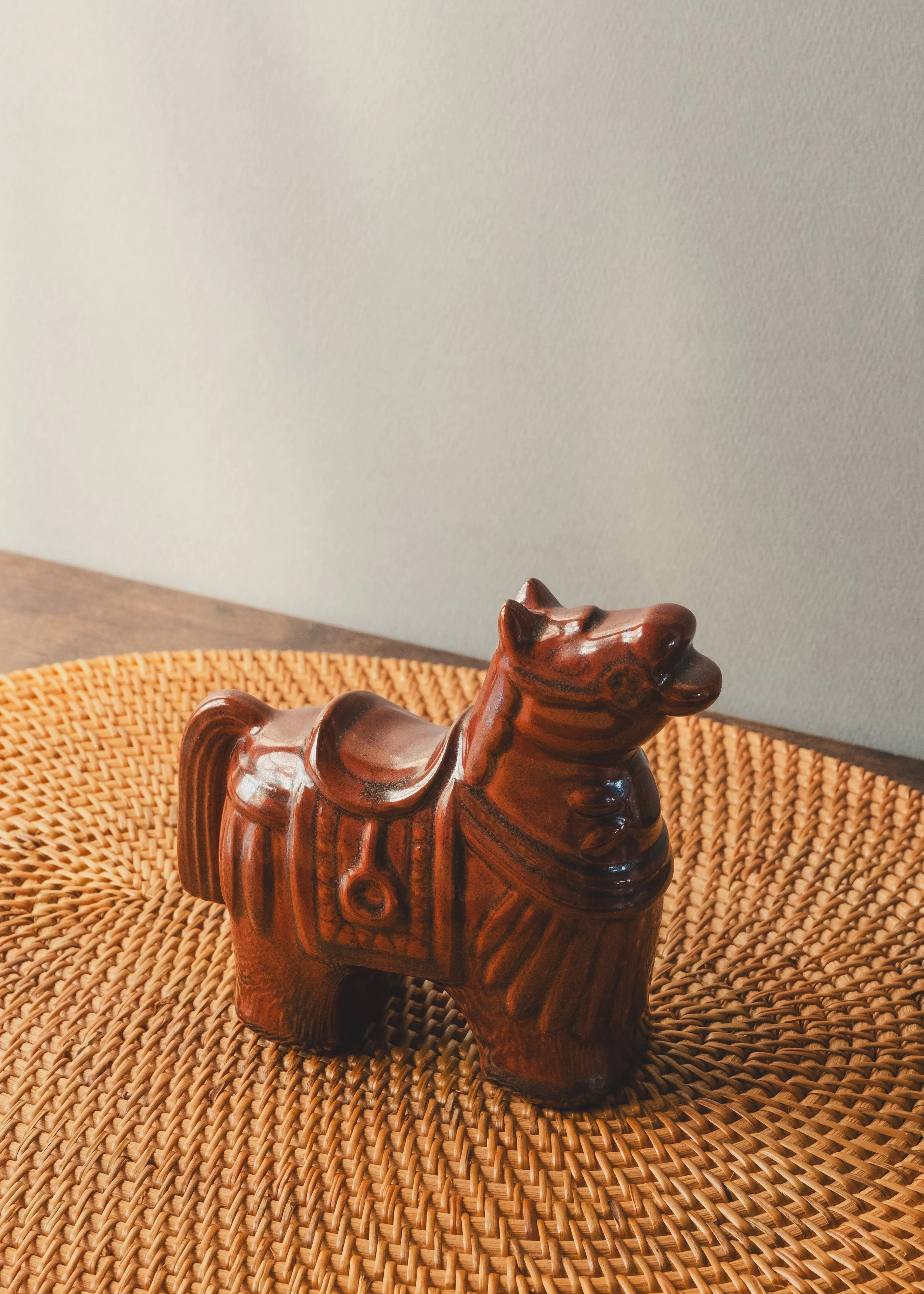 Hand-painted brown glazed pottery horse with traditional saddle relief design.