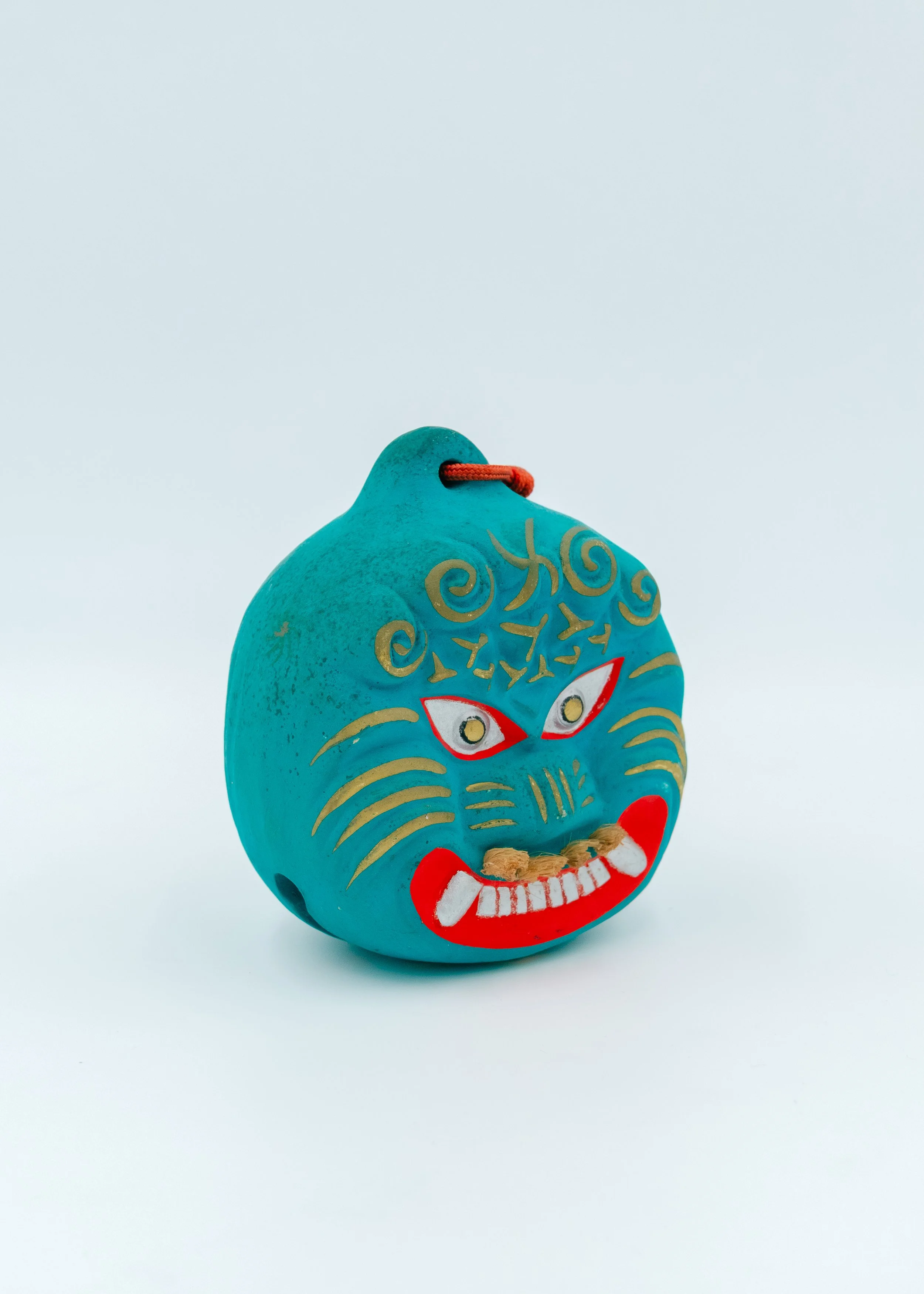 Vivid turquoise Nogomi Lion (Shishi-gashira) pottery bell from Saga, Japan, featuring a hand-painted gold mane and red ritual accents on a white shell powder base.