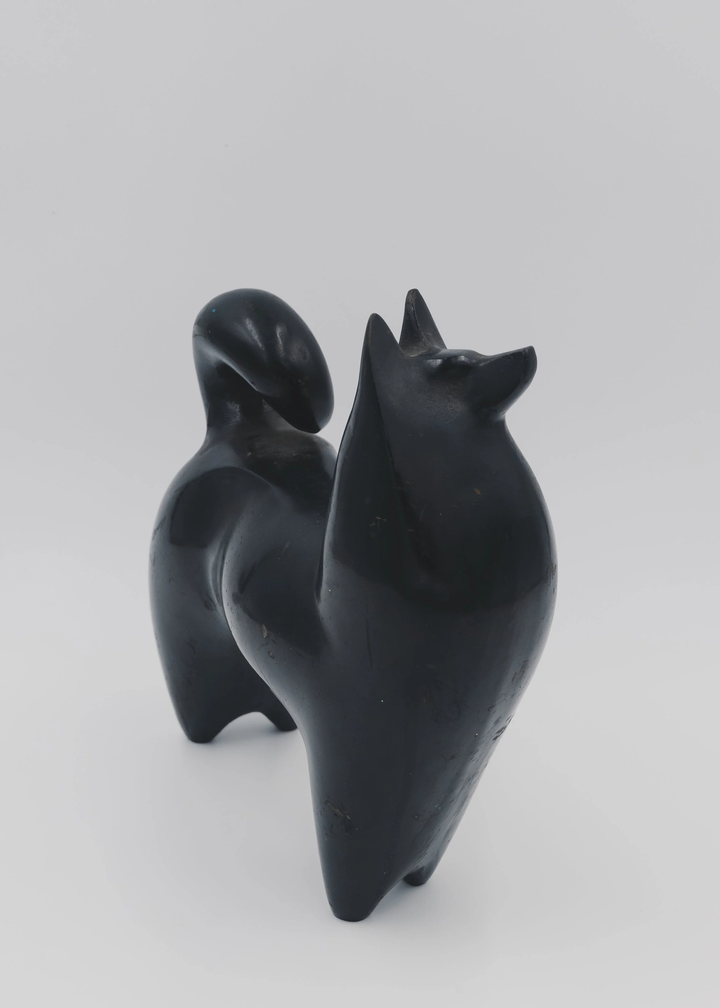 Side view of a vintage Nambu Tekki cast iron dog sculpture with a traditional curled tail (Maki-o) and nocturnal black finish, Japandi style decor.