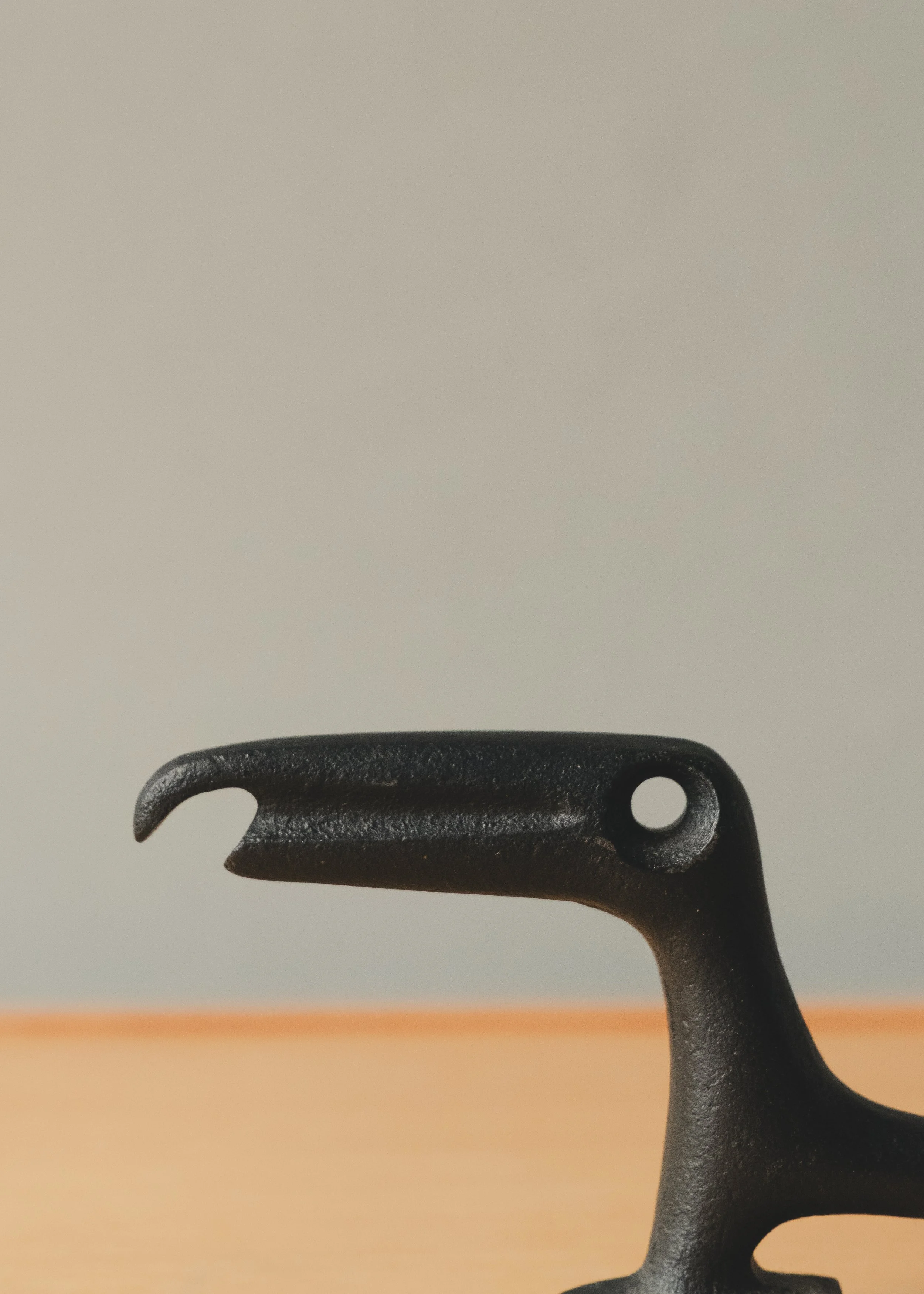 Macro shot of the raven's head and beak silhouette, highlighting the organic curves and unglazed material honesty created through traditional sand-casting techniques.